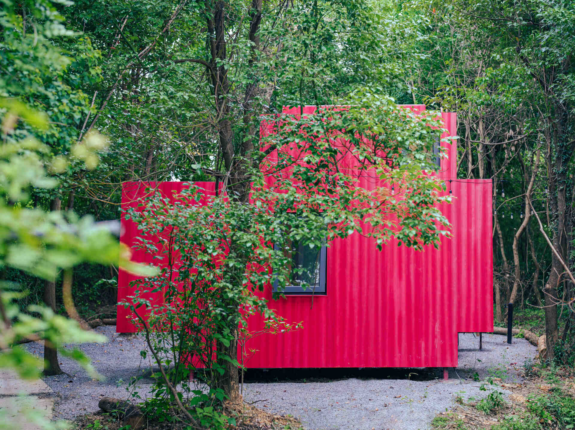 Wiki World’s Red Submarine Cabin brings the playful feeling of a submarine into the forest, with a vibrant red exterior, circular portholes and a compact timber interior.