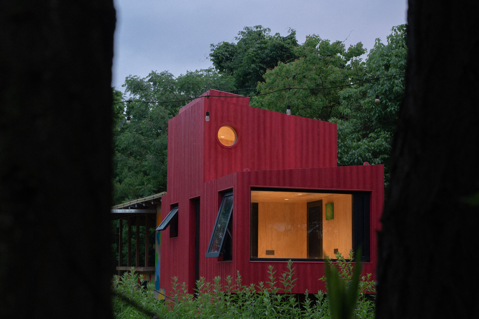 Wiki World’s Red Submarine Cabin brings the playful feeling of a submarine into the forest, with a vibrant red exterior, circular portholes and a compact timber interior.