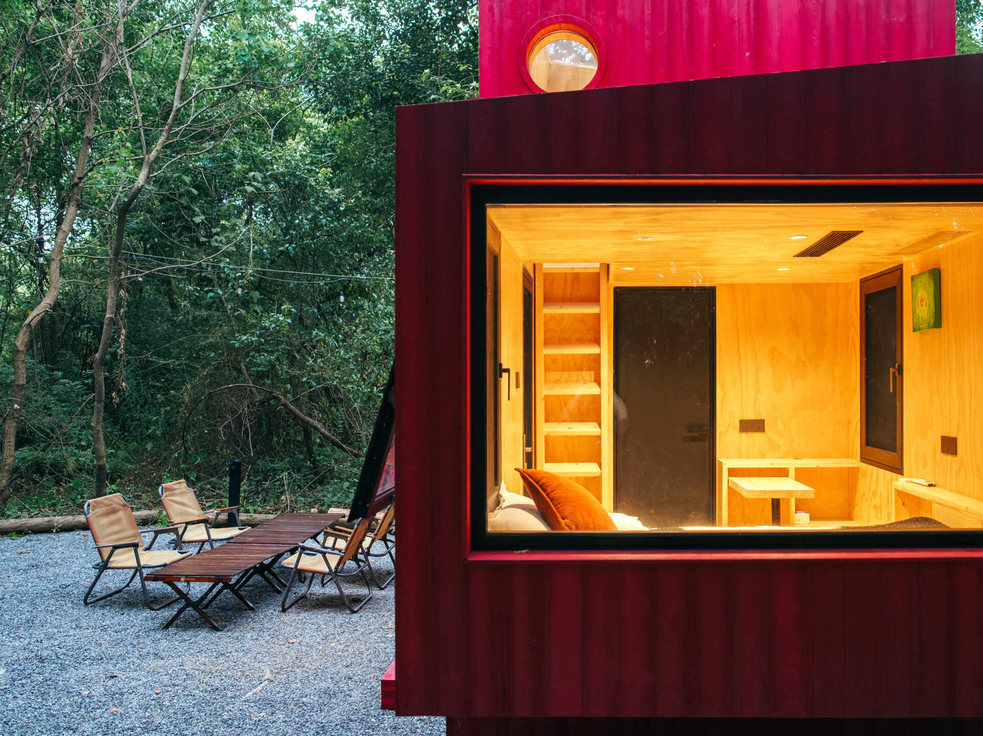 Wiki World’s Red Submarine Cabin brings the playful feeling of a submarine into the forest, with a vibrant red exterior, circular portholes and a compact timber interior.