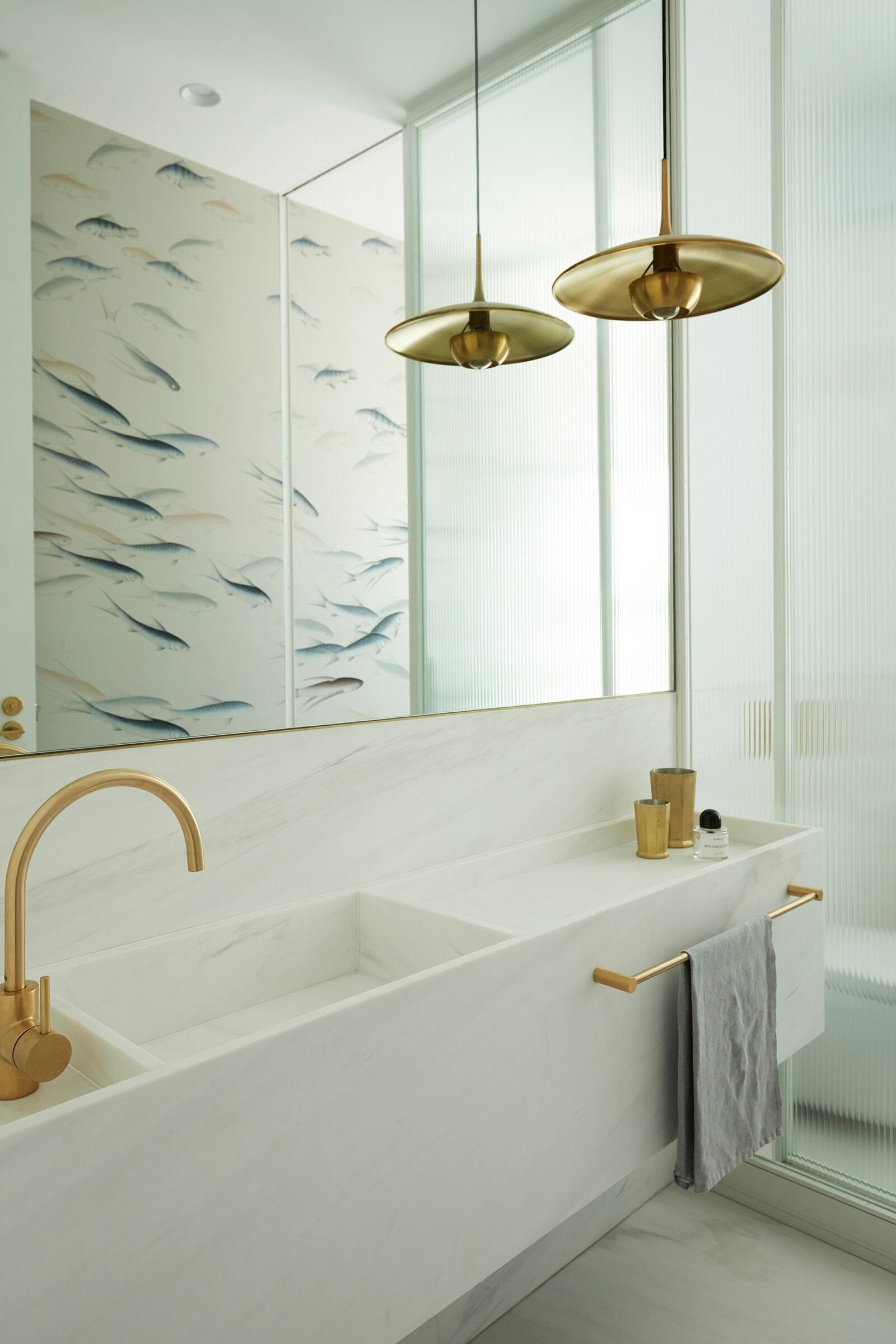 A white vanity and integrated basin sit beneath a large mirror, while a playful fish pattern adds character to this modern bathroom in Bellevue Hill.