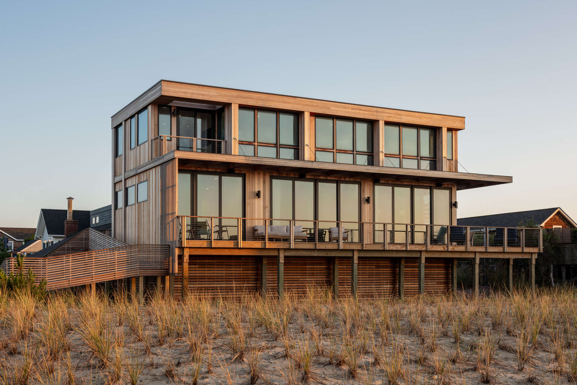 Explore the cedar-clad architecture of Surf Road House by Coughlin Scheel Architects in Ocean Beach, Fire Island. Elevated on timber pilings, this coastal home combines ocean-facing windows, layered facades, and a shaded wood trellis.