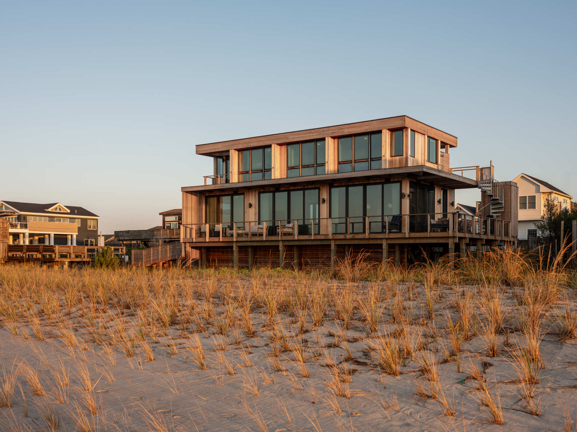 Explore the cedar-clad architecture of Surf Road House by Coughlin Scheel Architects in Ocean Beach, Fire Island. Elevated on timber pilings, this coastal home combines ocean-facing windows, layered facades, and a shaded wood trellis.
