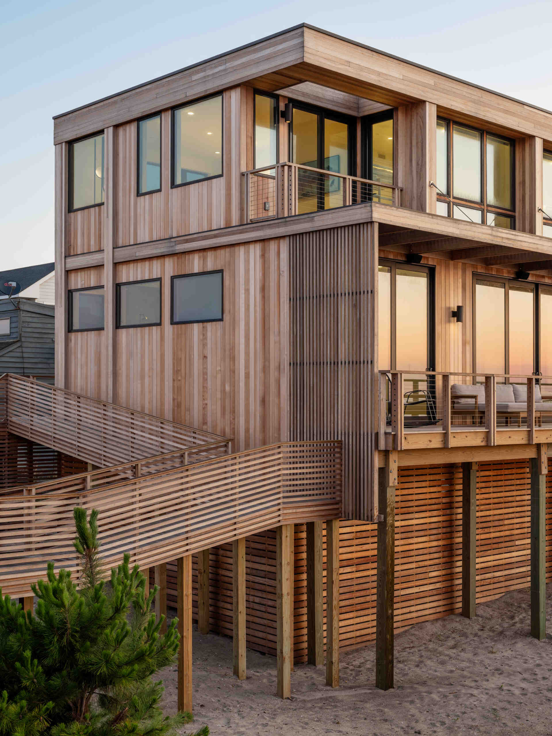Explore the cedar-clad architecture of Surf Road House by Coughlin Scheel Architects in Ocean Beach, Fire Island. Elevated on timber pilings, this coastal home combines ocean-facing windows, layered facades, and a shaded wood trellis.