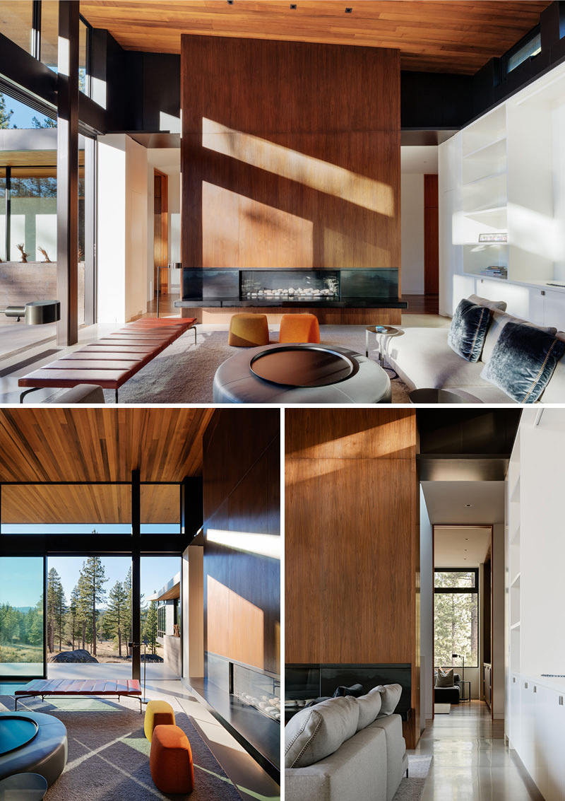 Inside the modern living room, a black steel fireplace and wood accent wall divide two hallways leading through the home.