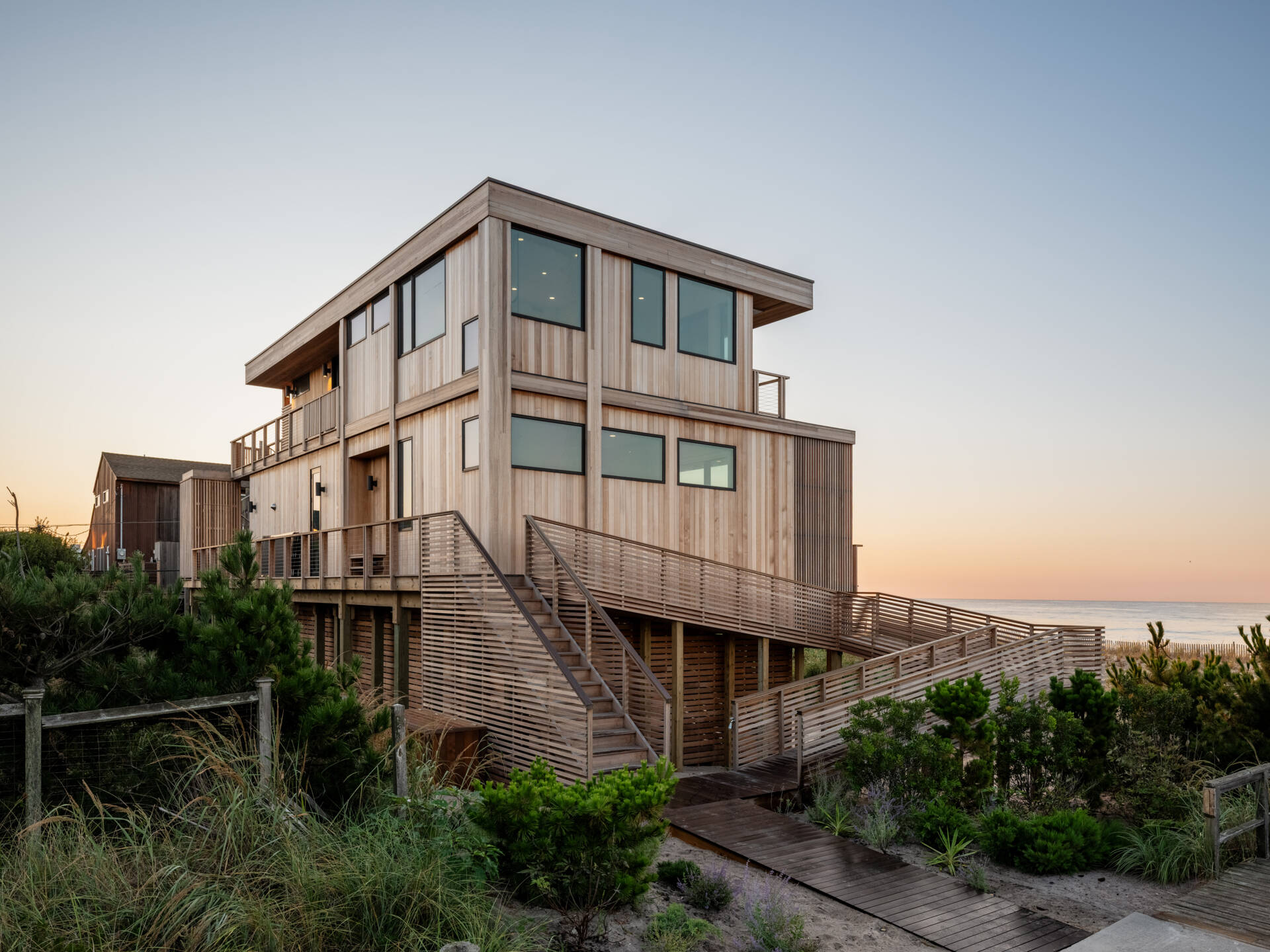 A long entrance ramp, outdoor steps, and a spiral stair shape the arrival at this elevated Fire Island home. Explore how Surf Road House brings a beach-town feel to coastal architecture.