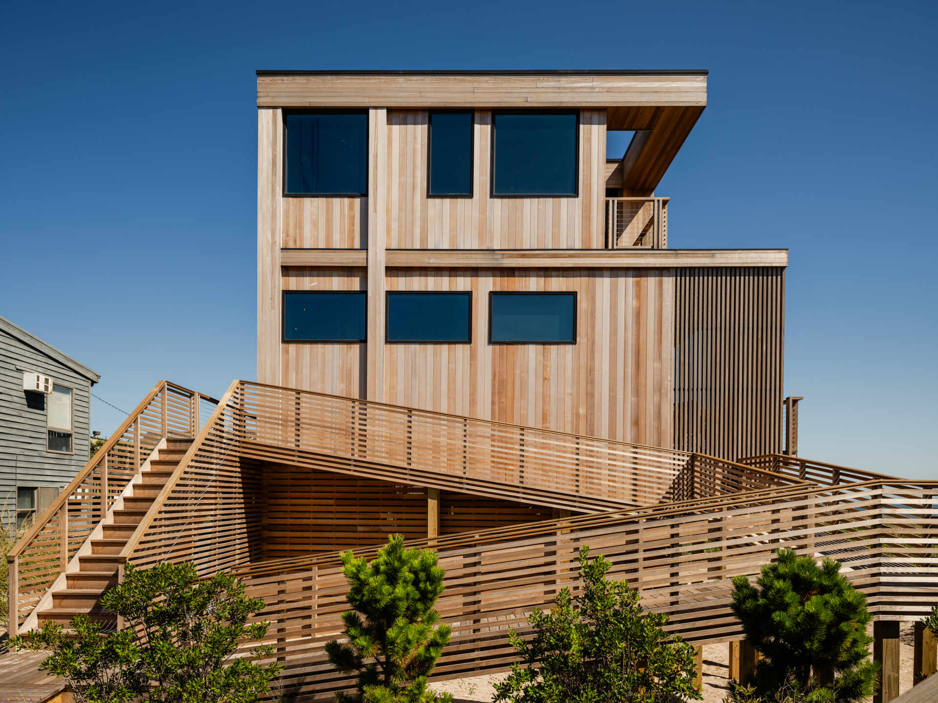 A long entrance ramp, outdoor steps, and a spiral stair shape the arrival at this elevated Fire Island home. Explore how Surf Road House brings a beach-town feel to coastal architecture.