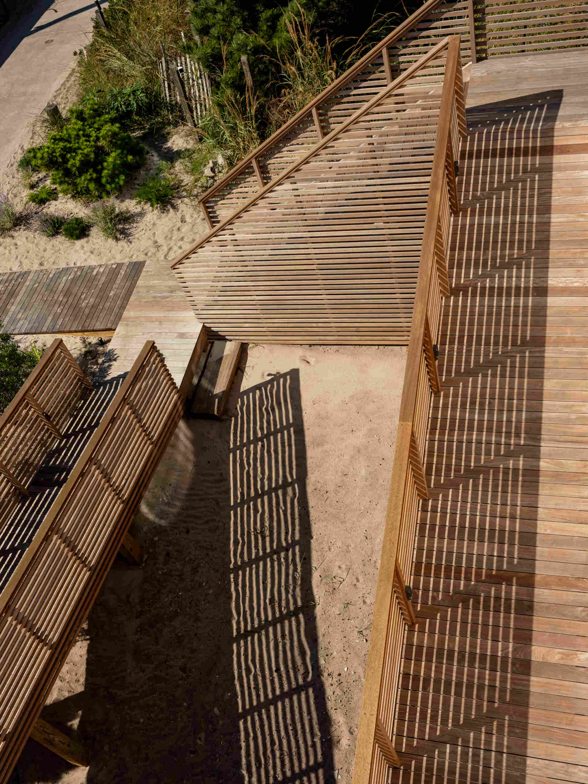 A long entrance ramp, outdoor steps, and a spiral stair shape the arrival at this elevated Fire Island home. Explore how Surf Road House brings a beach-town feel to coastal architecture.