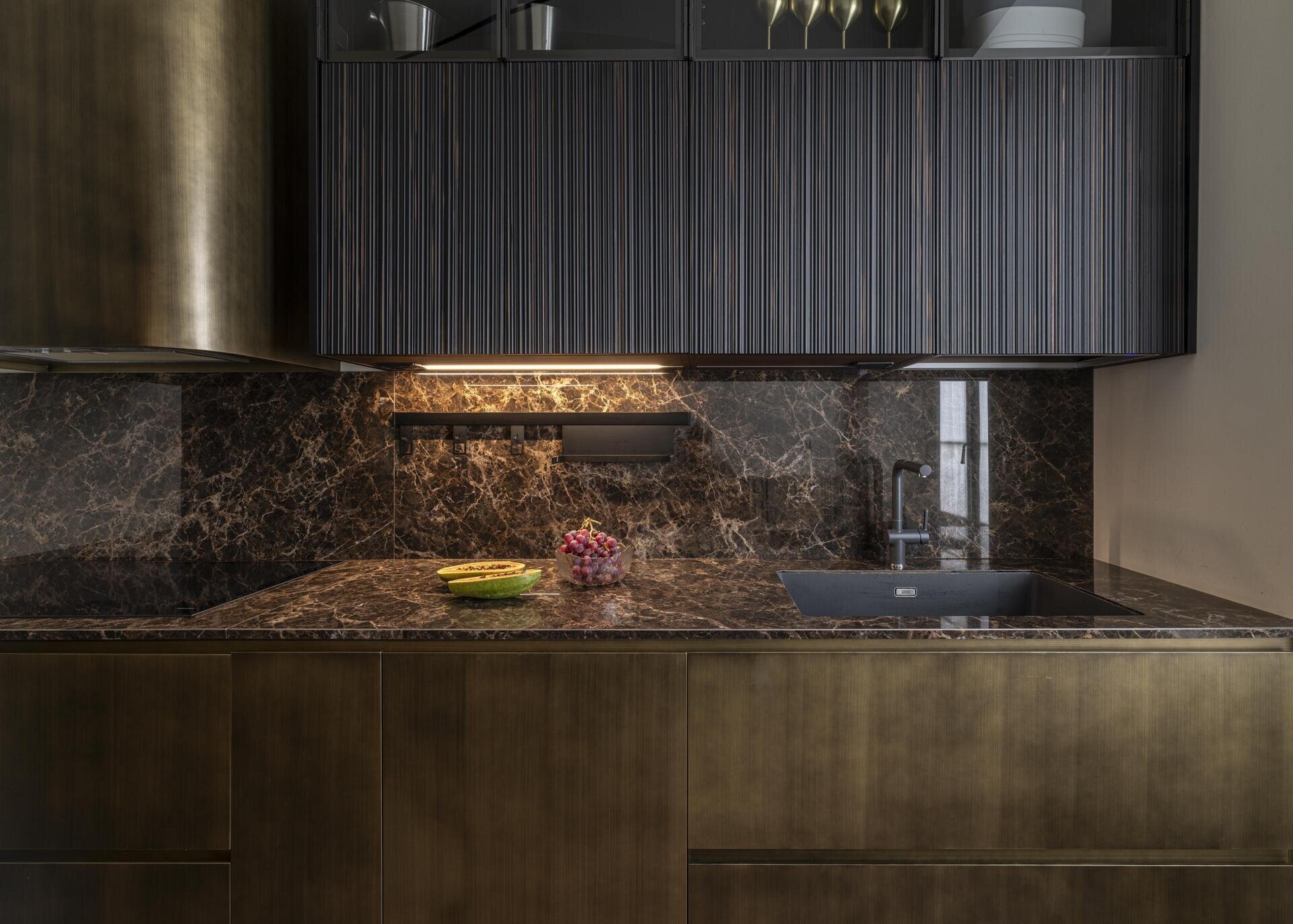 A compact Italian kitchen combines burnished brass cabinetry, irregular wooden reeded panelling and bespoke furniture designed specifically for a young family.
