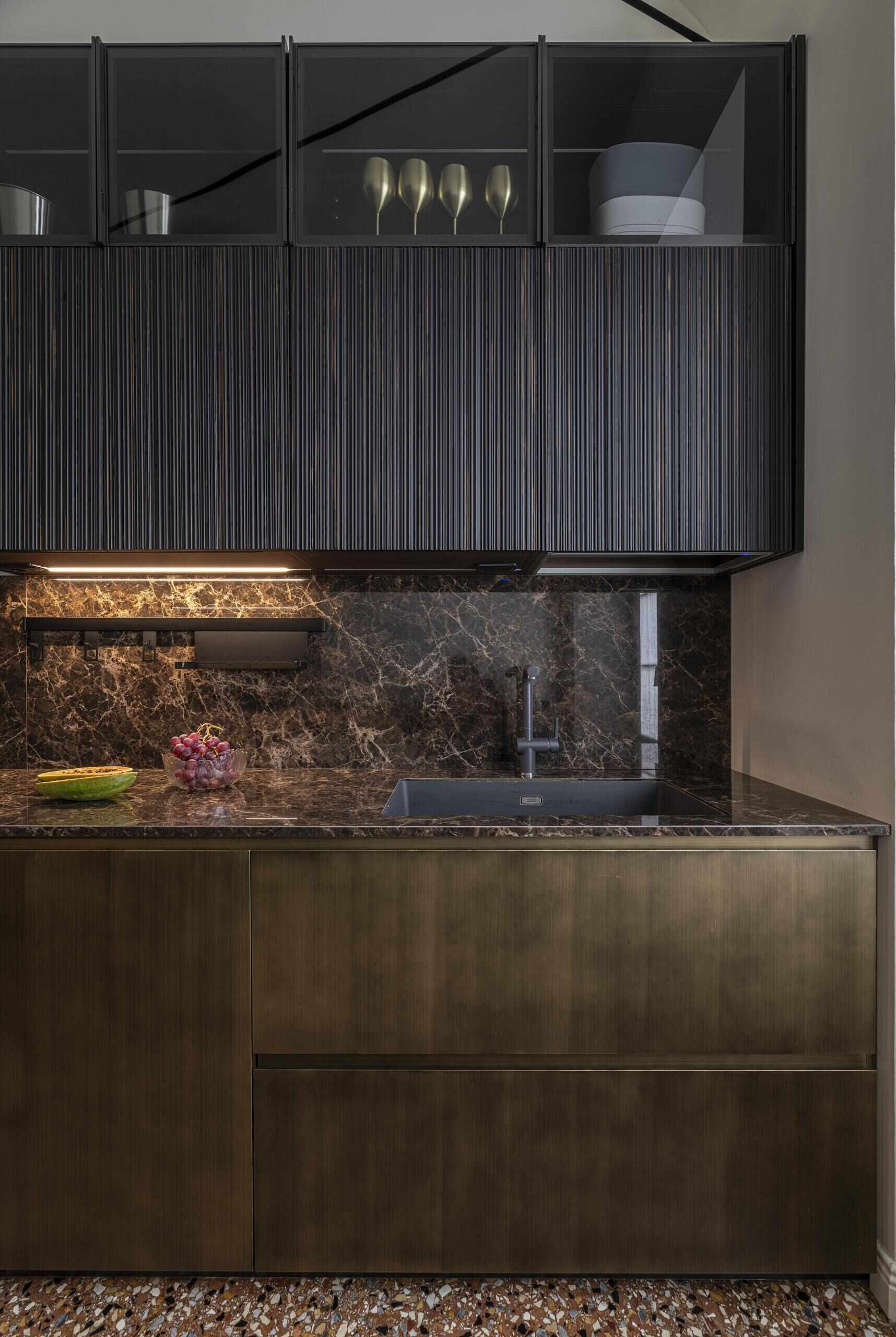 A compact Italian kitchen combines burnished brass cabinetry, irregular wooden reeded panelling and bespoke furniture designed specifically for a young family.