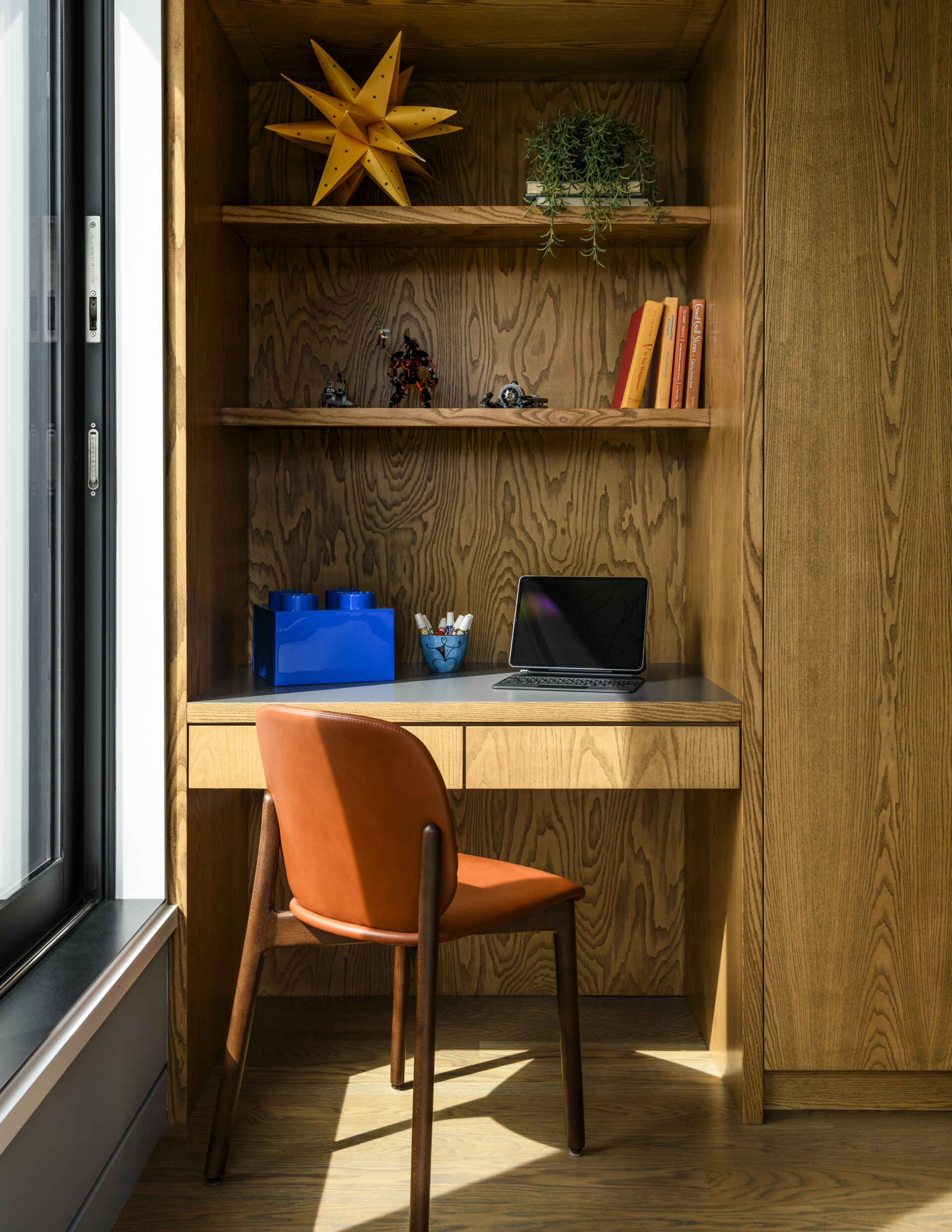 Featuring custom wood bunk beds, stainless steel railings, nautical wallpaper on the ceiling, a built-in desk, and warm orange accents, this compact bedroom combines playful design with practical storage.