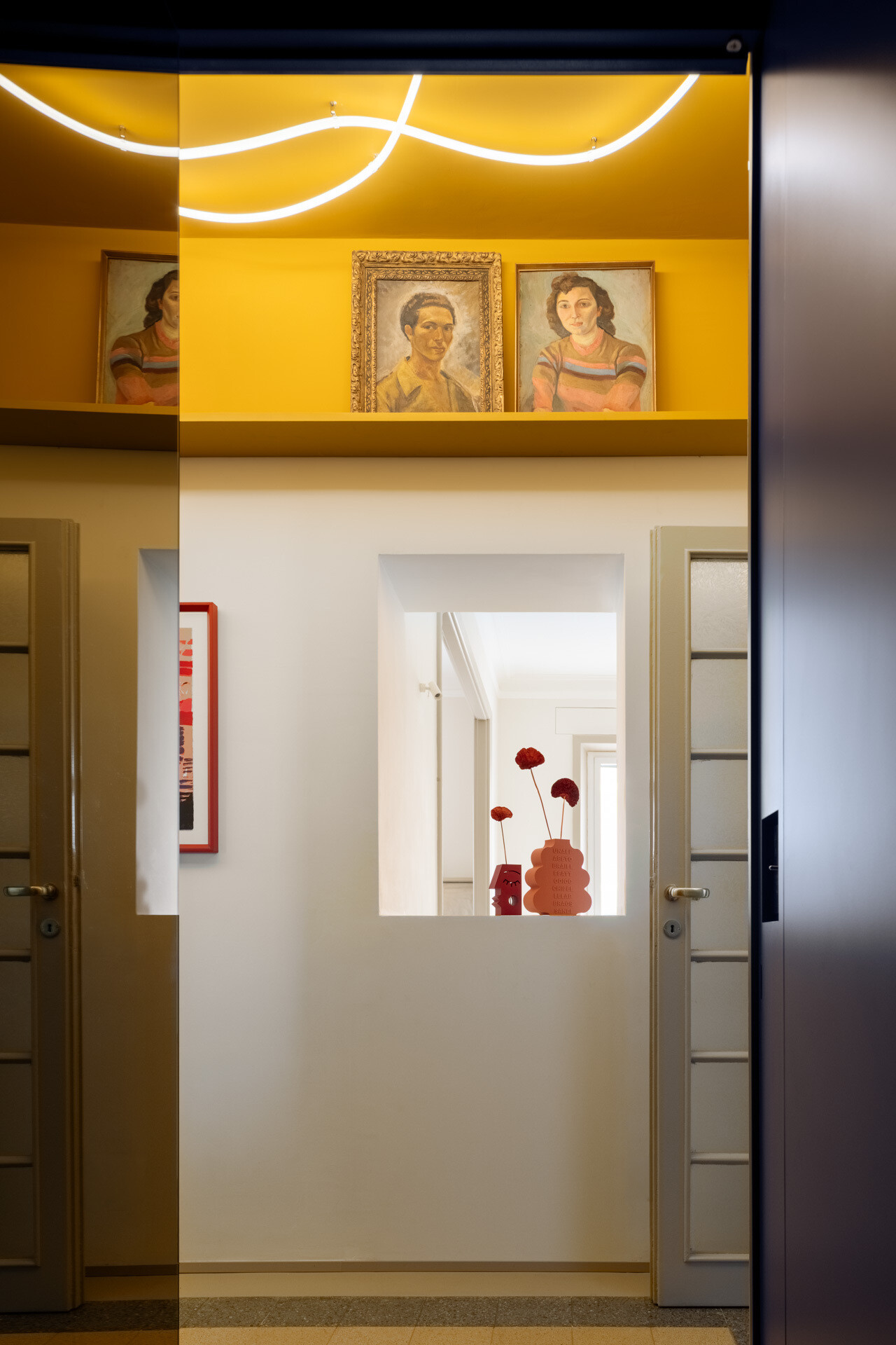 A unique apartment hallway in Rome features a vivid yellow ceiling with custom white LED neon lighting inspired by Lucio Fontana. Designed by Neeo Design as part of a renovation by Raffaella Falbo, the abstract light installation is reflected in a mirrored wall.