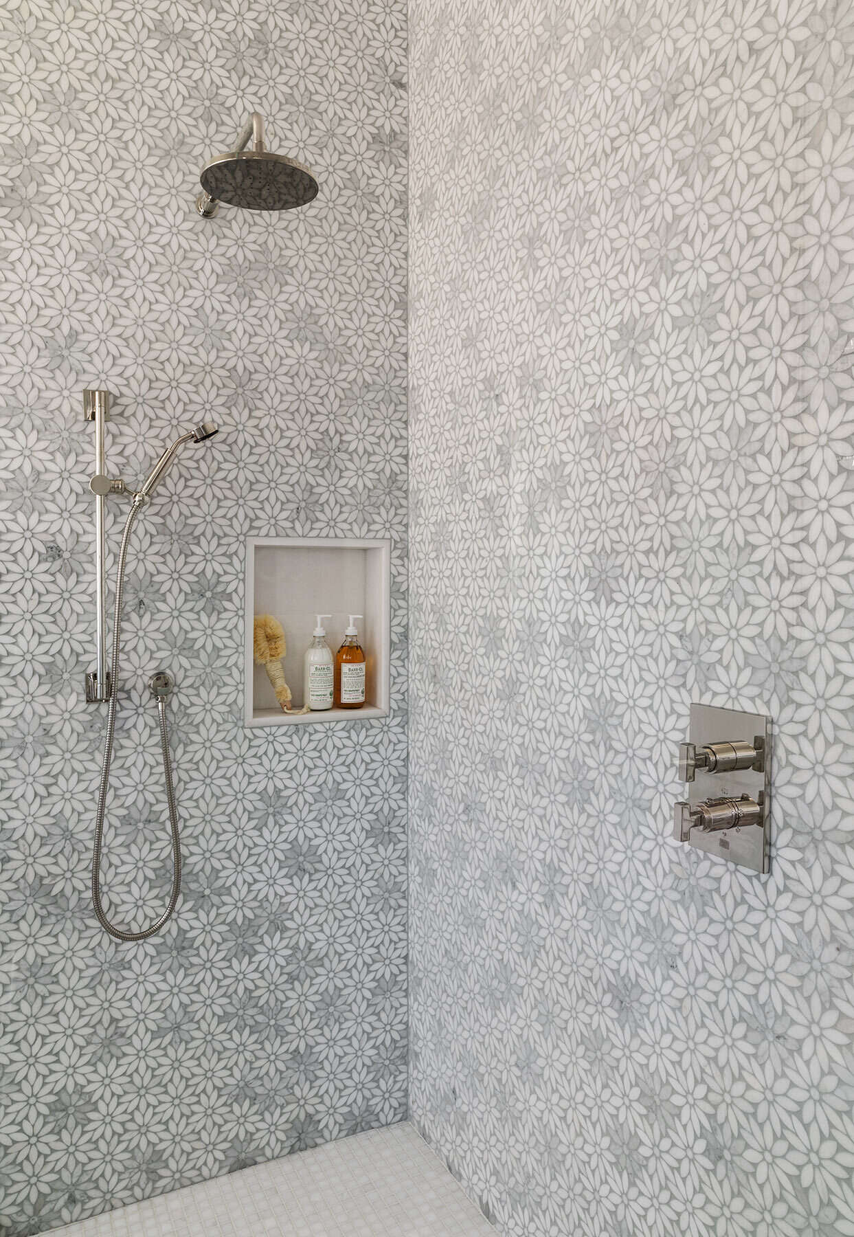 A second bathroom in the Atherton Residence pairs floral mosaic shower walls with a frameless glass enclosure, polished metal fittings and a pale blue vanity for a softer, more decorative take on modern bathroom design.
