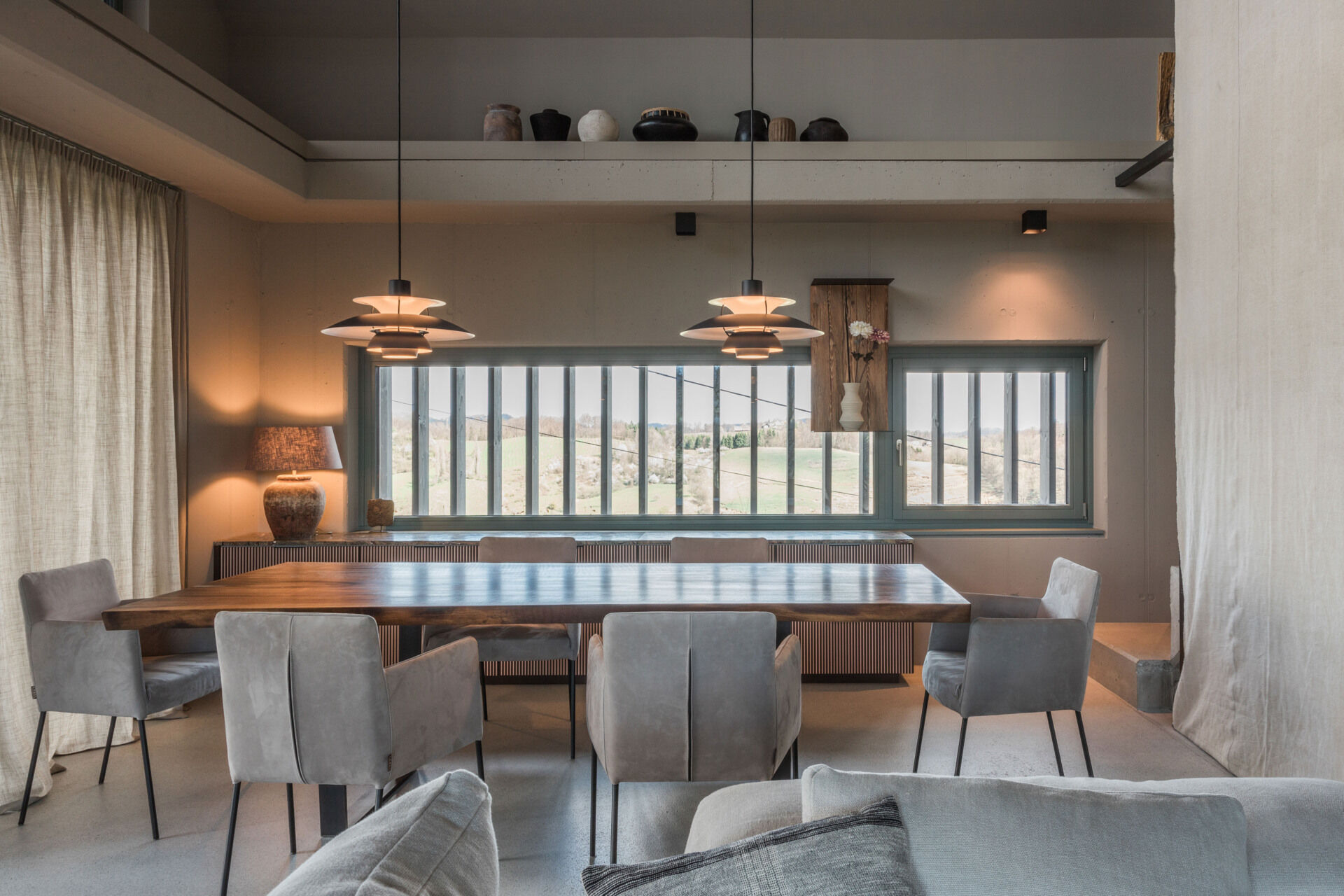 Discover a contemporary farmhouse dining room featuring a large timber table, upholstered chairs, sculptural pendant lighting, and custom grooved cabinetry.
