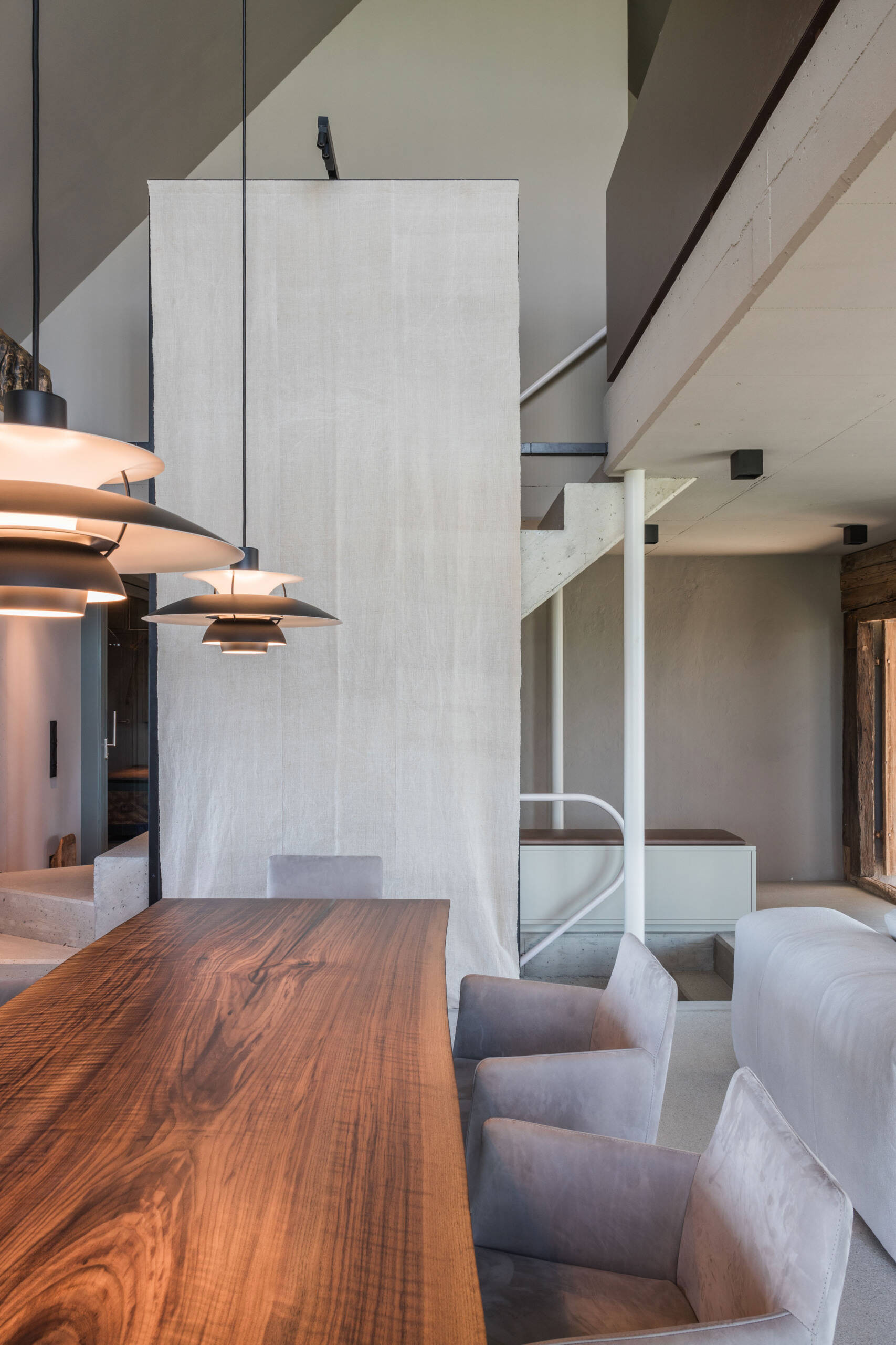 Discover a contemporary farmhouse dining room featuring a large timber table, upholstered chairs, sculptural pendant lighting, and custom grooved cabinetry.