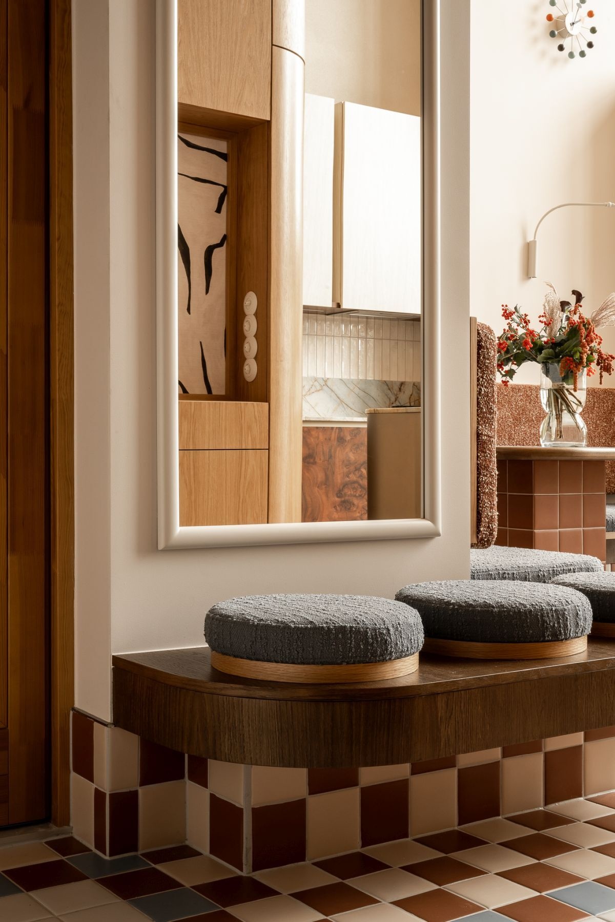 A colorful contemporary entryway with geometric mosaic floor tiles, custom wood cabinetry, a large illuminated mirror, and built-in seating at Kalbornia Lake & Pool House in Poland.