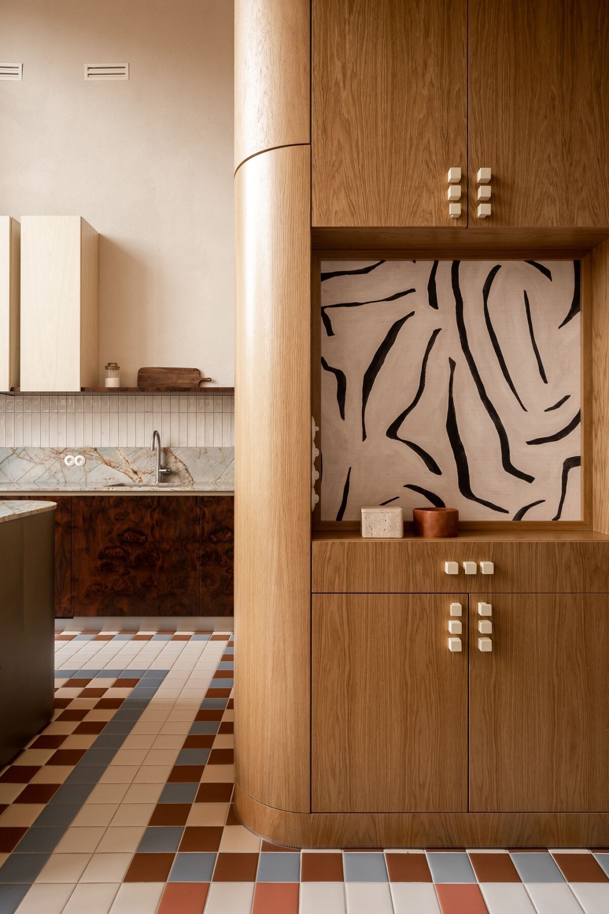 A colorful contemporary entryway with geometric mosaic floor tiles, custom wood cabinetry, a large illuminated mirror, and built-in seating at Kalbornia Lake & Pool House in Poland.