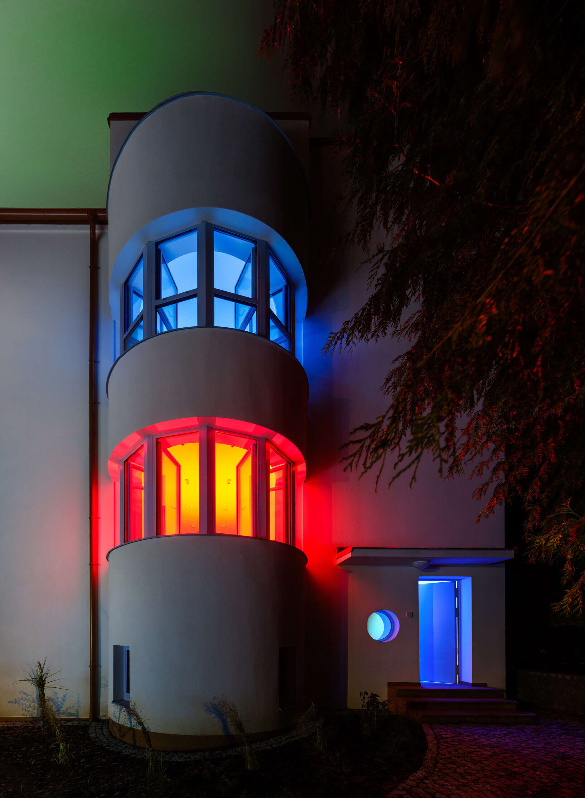 Discover the exterior transformation of Blue Window House in Prague, Czech Republic, by No Architects. The renovated modernist home features a white facade, curved window bays, distinctive blue aluminum window frames, and a redesigned garden.