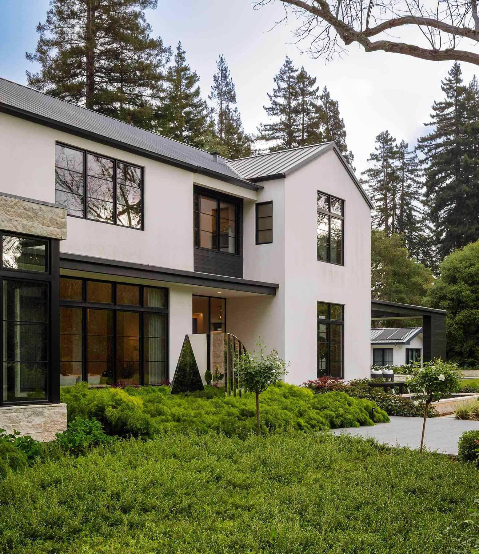 Tour the exterior and backyard of the Atherton Residence by SDG Architecture, where pale gabled volumes, black-framed windows, stone accents, mature landscaping and a large pool create a clean contemporary setting.