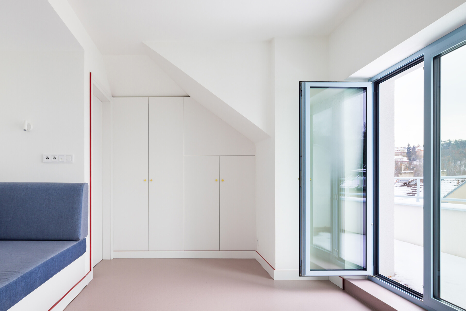 Explore the contemporary bedroom designs inside Blue Window House, featuring vertical timber wall panels, custom wooden wardrobes, integrated bedside shelves, and subtle lighting. Natural wood finishes and a red upholstered bed frame bring warmth and color to the minimalist interiors.