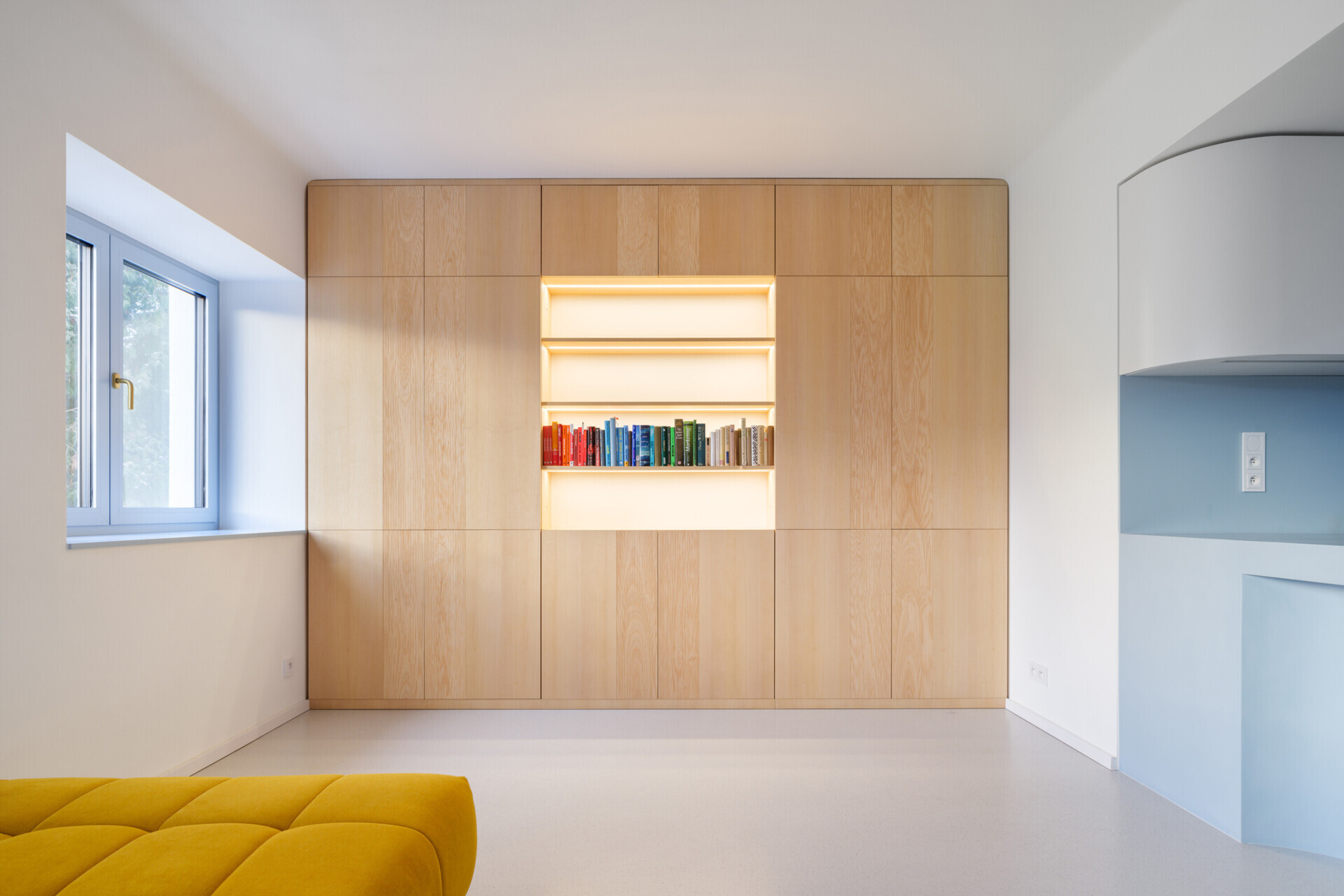 Explore the colorful living spaces of Blue Window House, where mustard-yellow seating, red pendant lights, warm wood cabinetry, and pale blue kitchens create playful contemporary interiors. Curved furniture, built-in storage, and custom joinery add character throughout the renovated home.