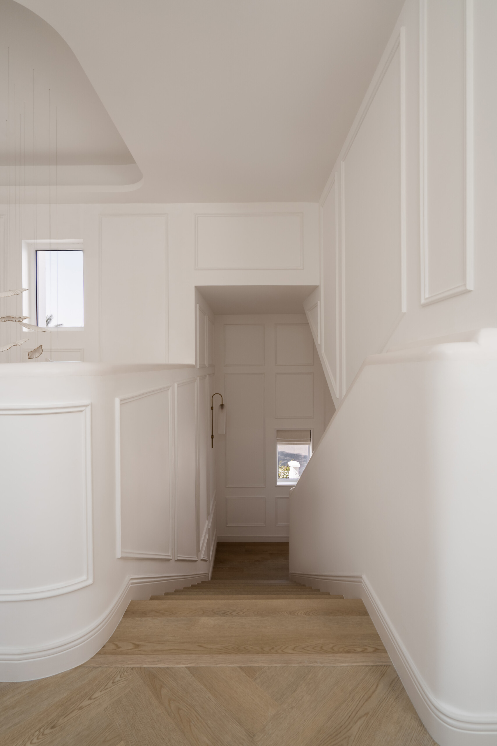 A beautifully renovated staircase inside The White Arcade in Dubai. D’Ora Tokai Designs transformed the original angular staircase with curved architectural details, oak steps, elegant white wall panelling, and a sculptural upper landing overlooking the central courtyard.