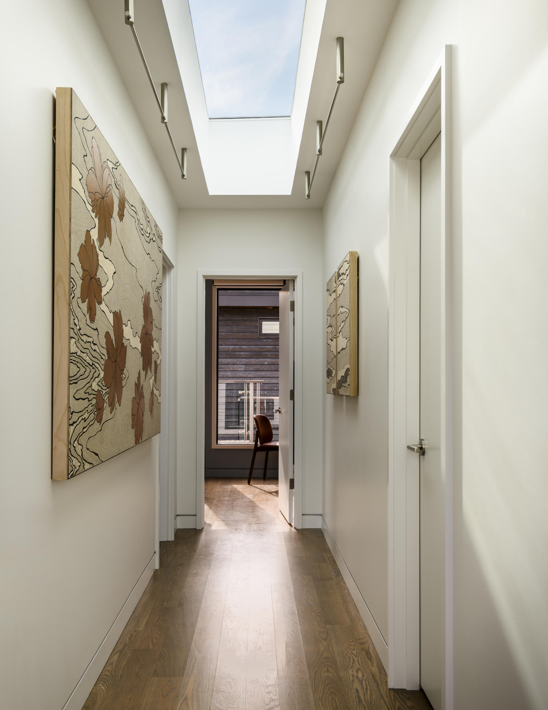 Open wood stairs, custom metal railings, translucent resin panels, weathered wood siding, and a skylit hallway bring modern and nautical design details together.