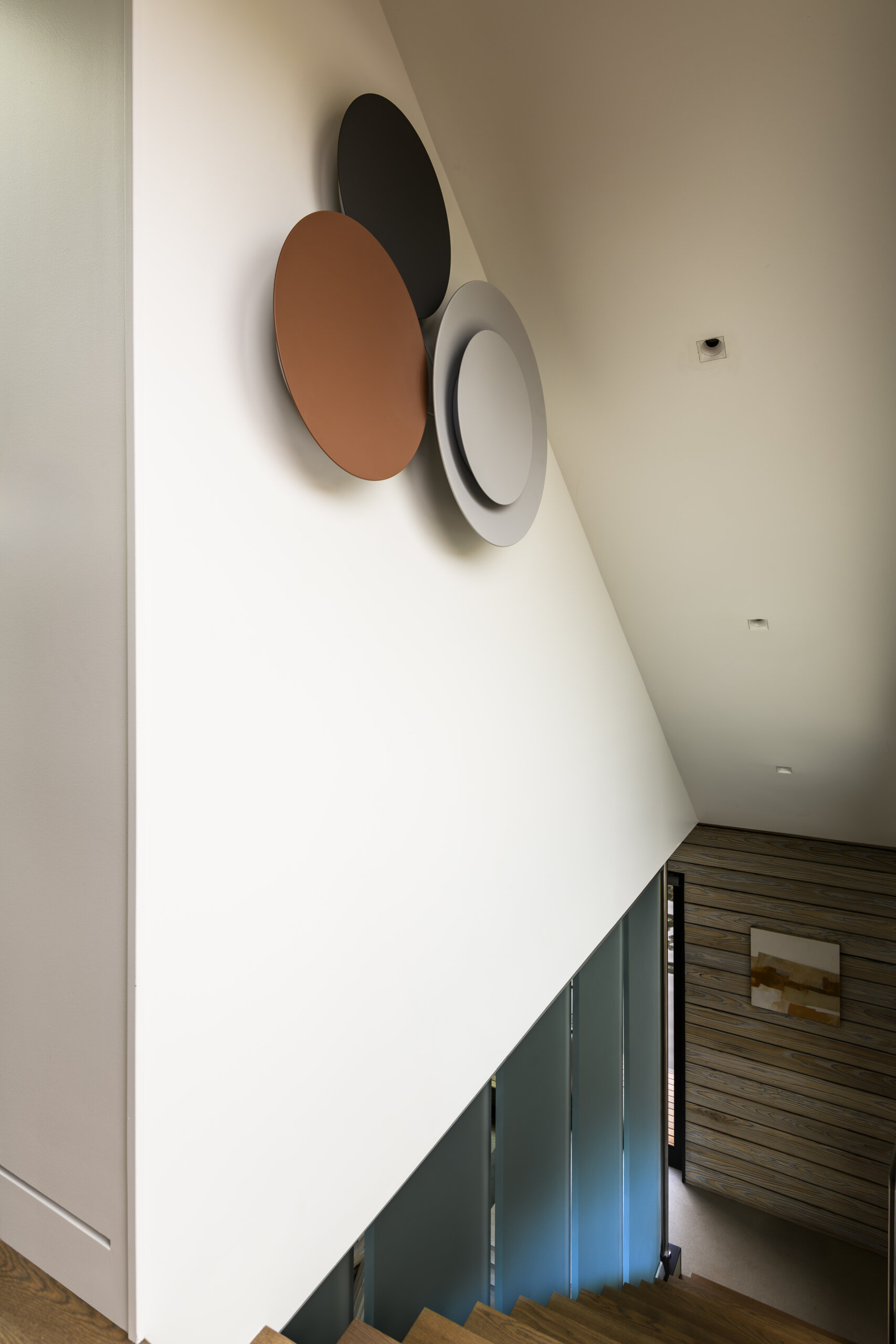 Open wood stairs, custom metal railings, translucent resin panels, weathered wood siding, and a skylit hallway bring modern and nautical design details together.