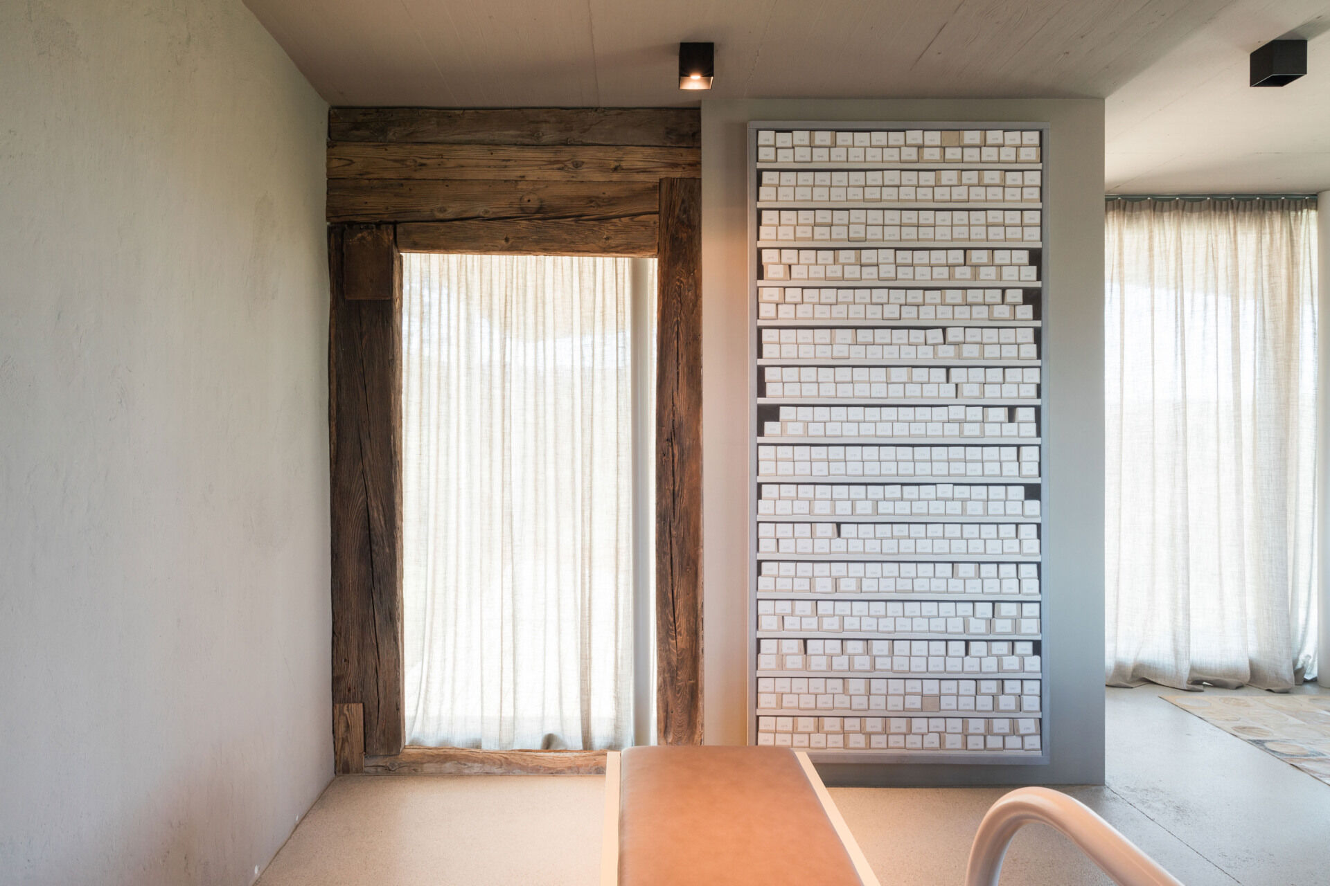 An Austrian farmhouse entryway combines weathered timber, a stone bench, linen curtains, and a modern interior with unusual architectural details.