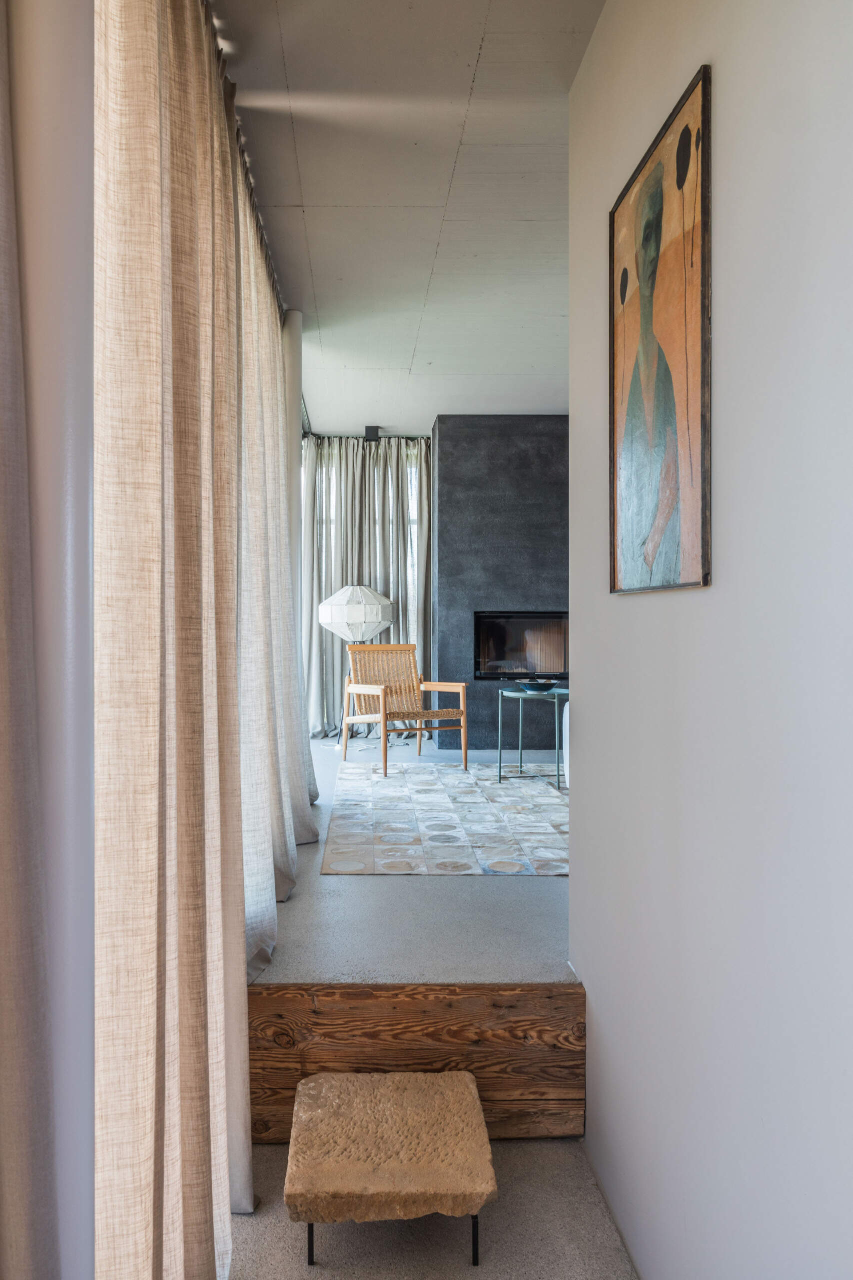 An Austrian farmhouse entryway combines weathered timber, a stone bench, linen curtains, and a modern interior with unusual architectural details.