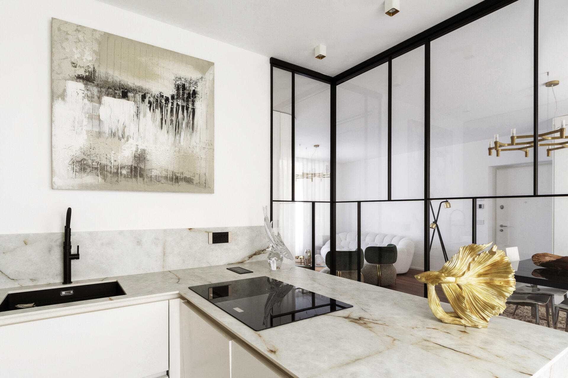 A glass-enclosed kitchen in a Turin apartment features floor-to-ceiling black metal frames, a sliding glass door, minimalist cabinetry, and marble-look countertops.