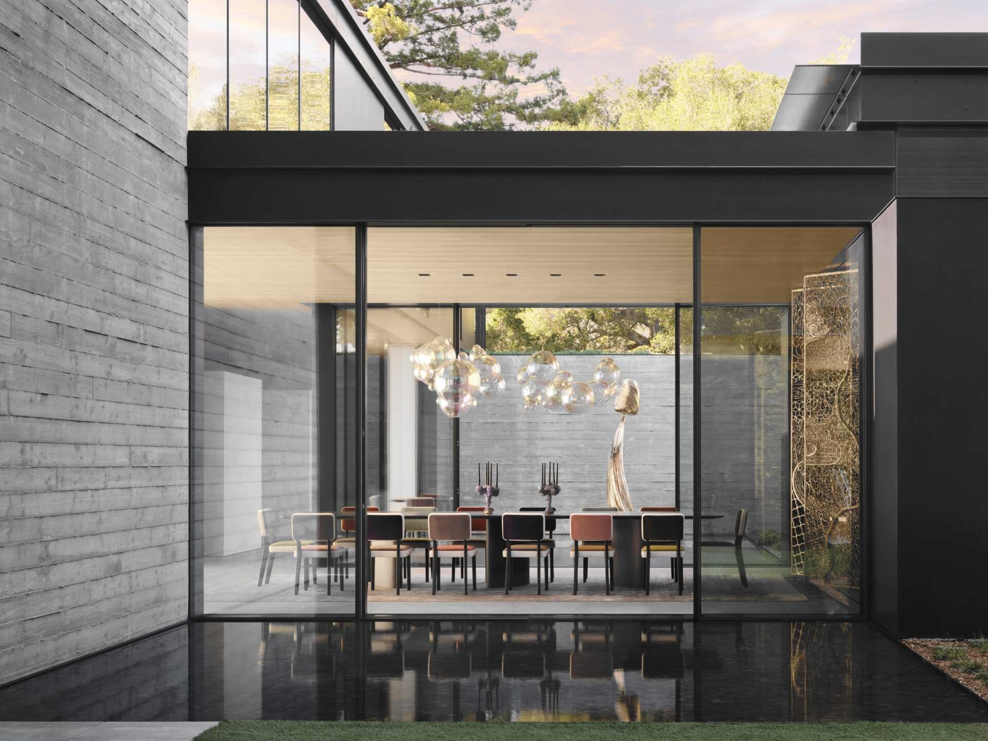 Explore a contemporary dining room with floor-to-ceiling glass walls, a long dining table, colorful upholstered dining chairs, and an incredible cluster of glass globe pendant lights. 
