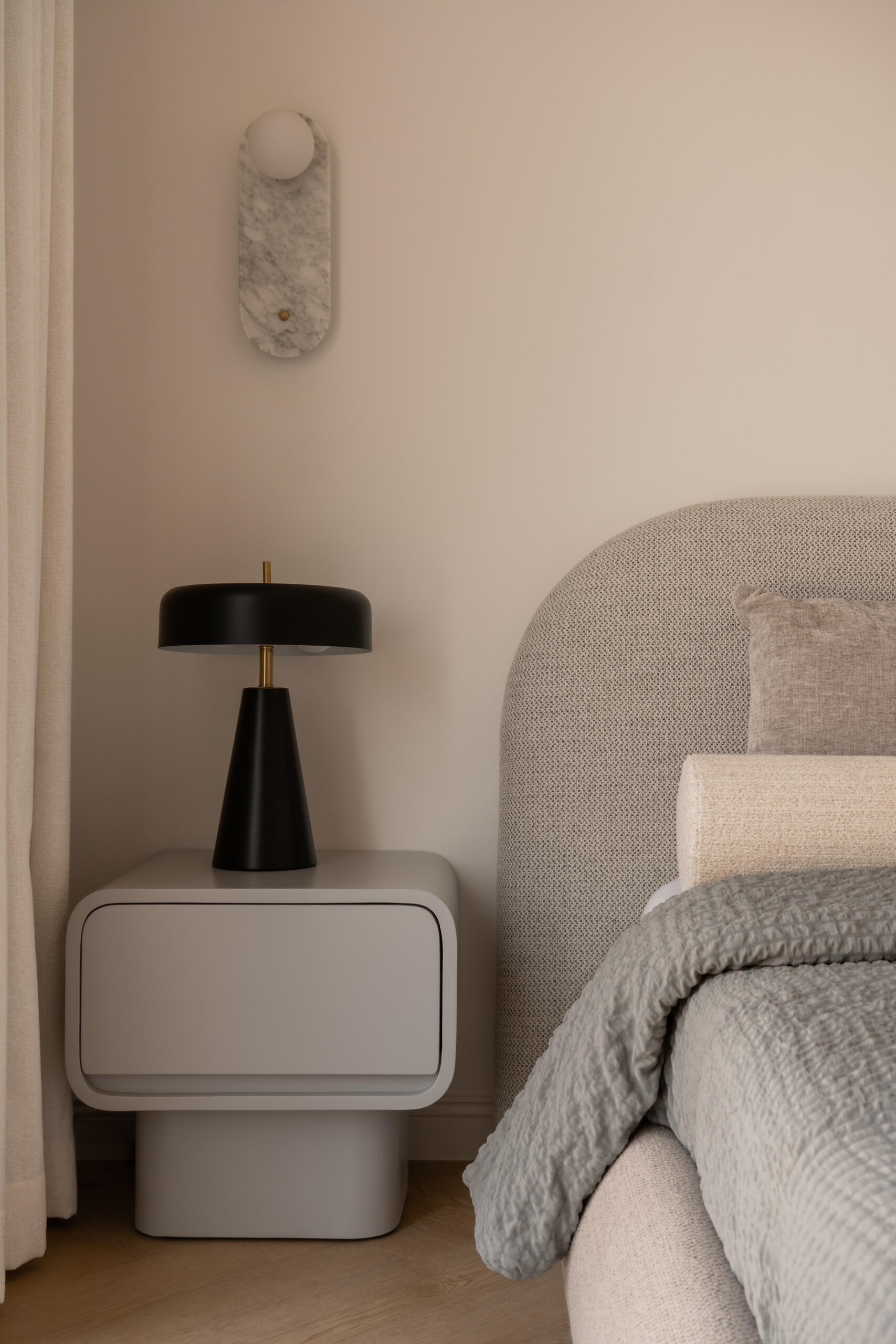 Neutral bedroom inspiration from The White Arcade in Dubai by D’Ora Tokai Designs. Explore contemporary bedrooms featuring rounded upholstered beds, textured bedding, sculptural bedside tables, marble wall lights, and soft beige and blue-grey colour palettes.