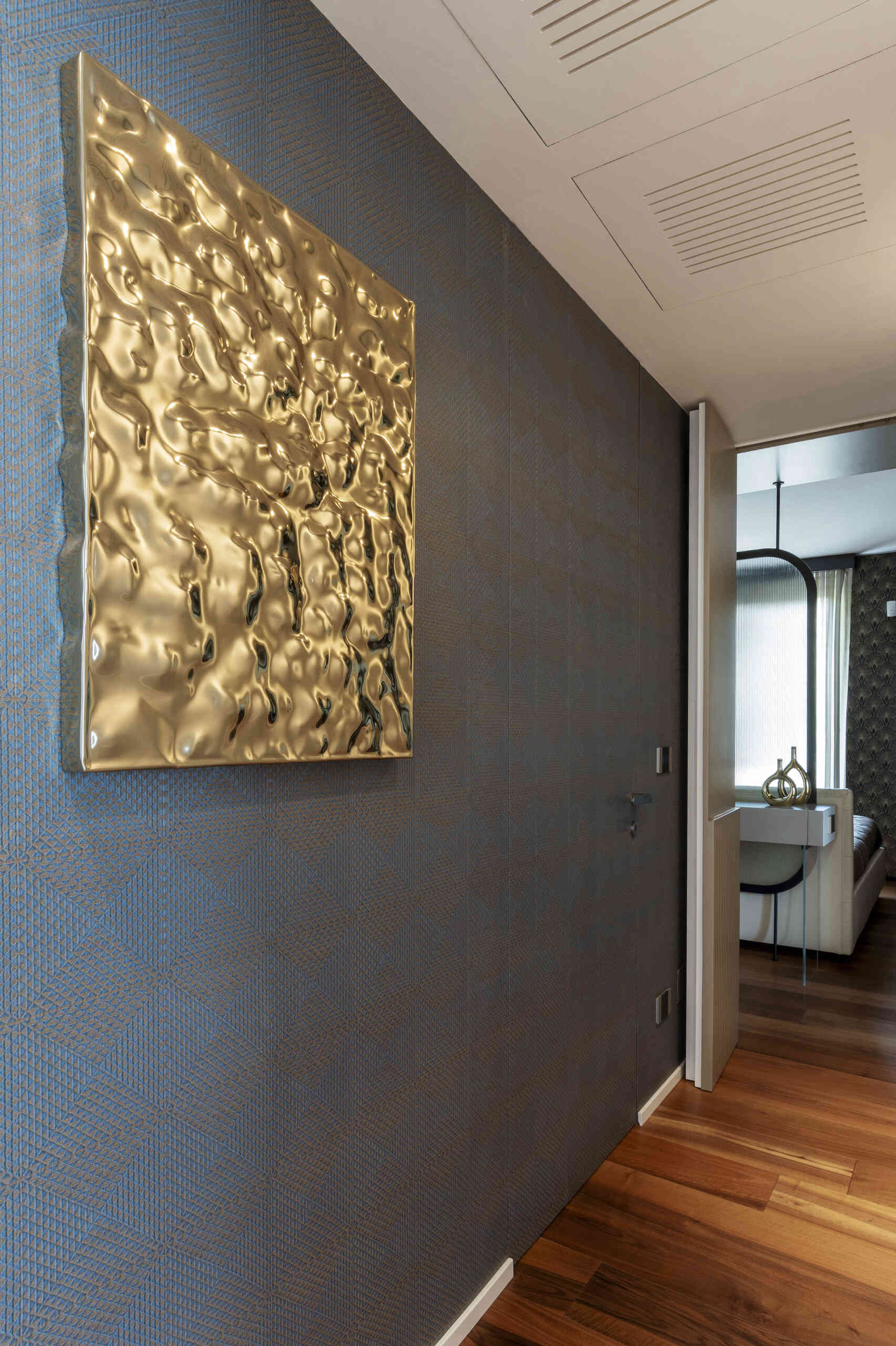 A hidden guest bathroom features dramatic tree-pattern wallpaper, a floating vanity, a large mirror, and a dark tiled shower, accessed from a textured hallway.