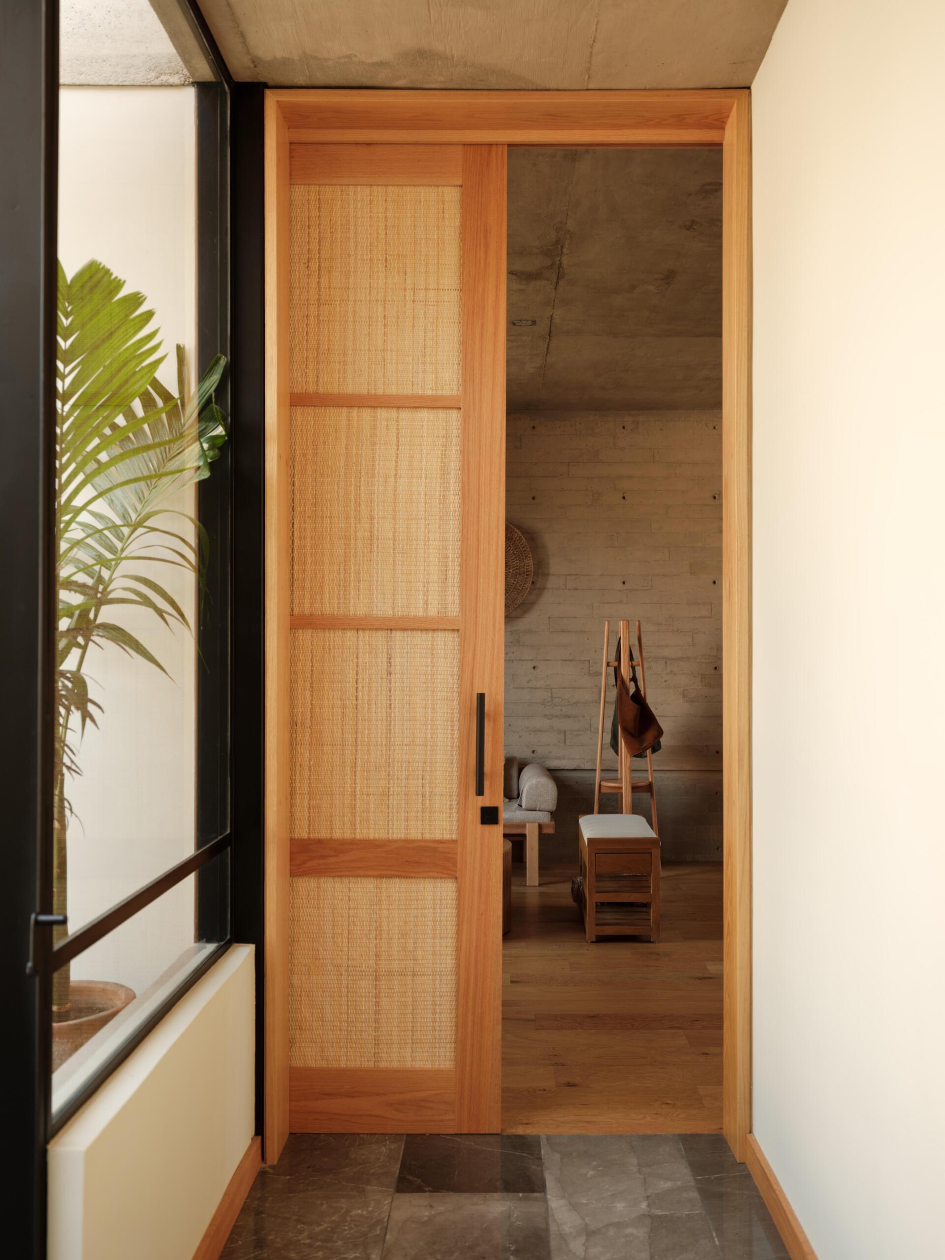 Explore a modern primary bedroom suite featuring a private sitting area, built-in bookshelves, woven sliding doors, a bedroom with geometric breeze-block screens, and a bathroom overlooking a planted courtyard.