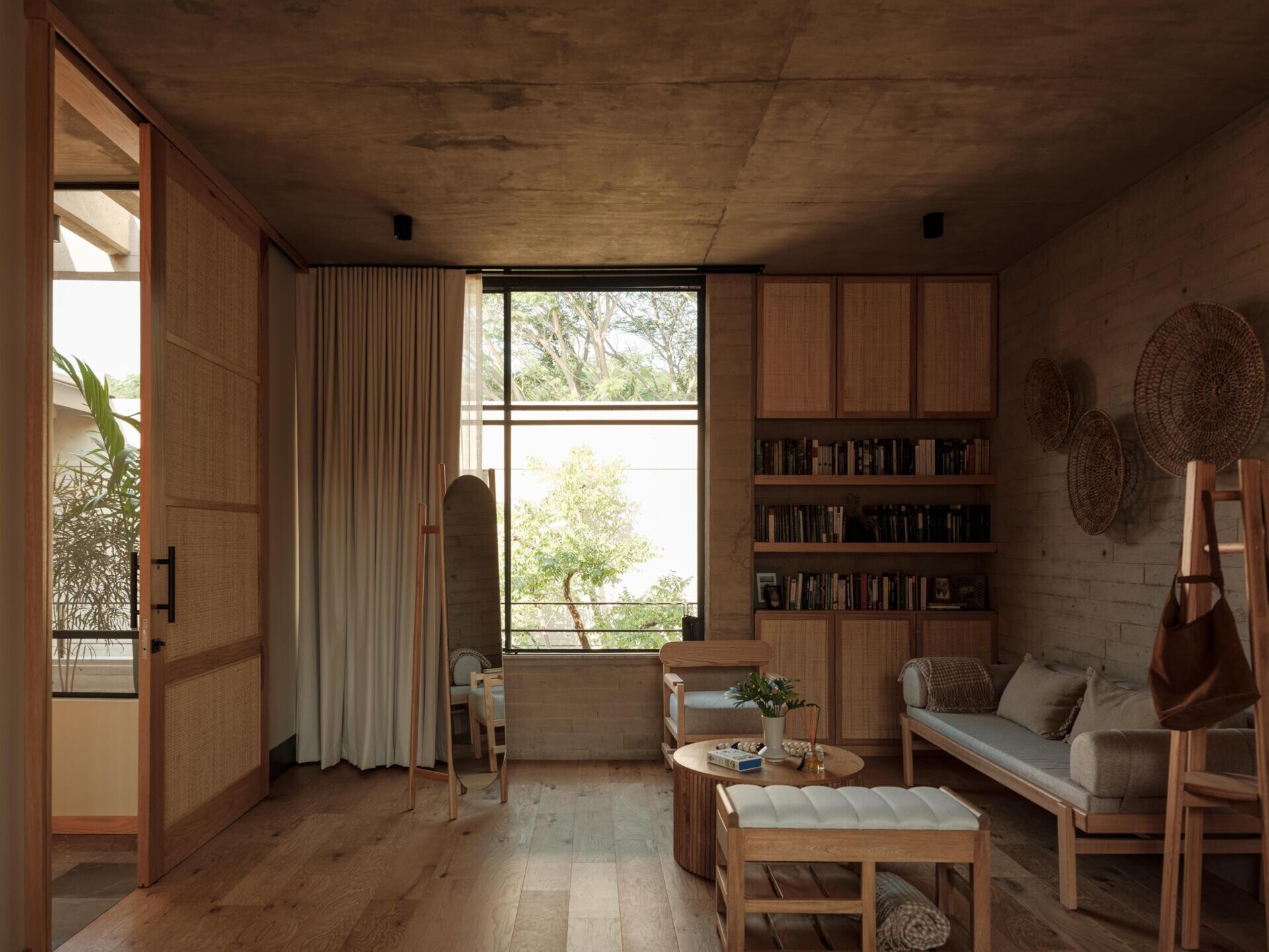 Explore a modern primary bedroom suite featuring a private sitting area, built-in bookshelves, woven sliding doors, a bedroom with geometric breeze-block screens, and a bathroom overlooking a planted courtyard.
