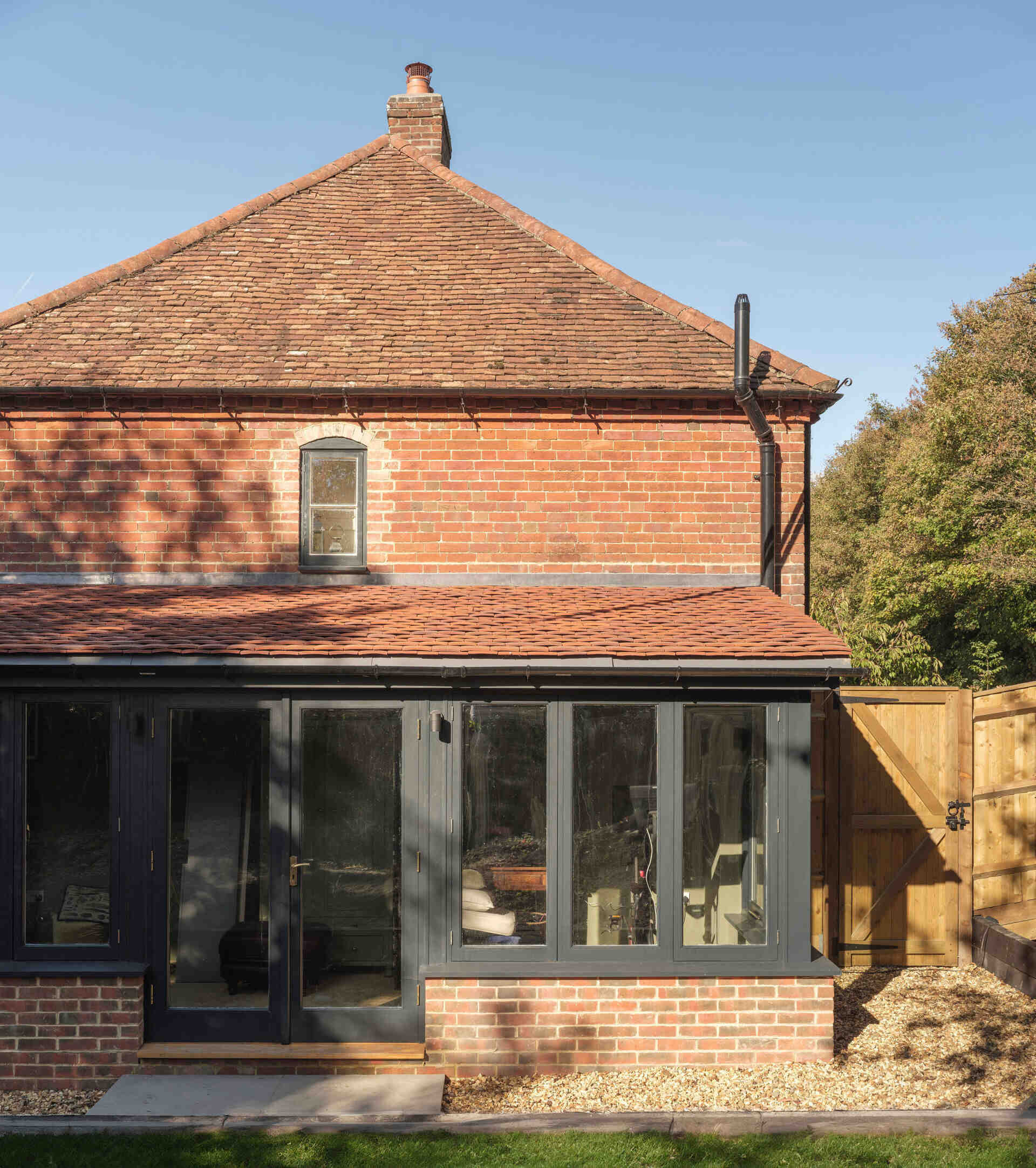 Traditional red brickwork, a pitched clay-tiled roof, and black-framed windows give this historic Hampshire cottage its character alongside a contemporary extension.