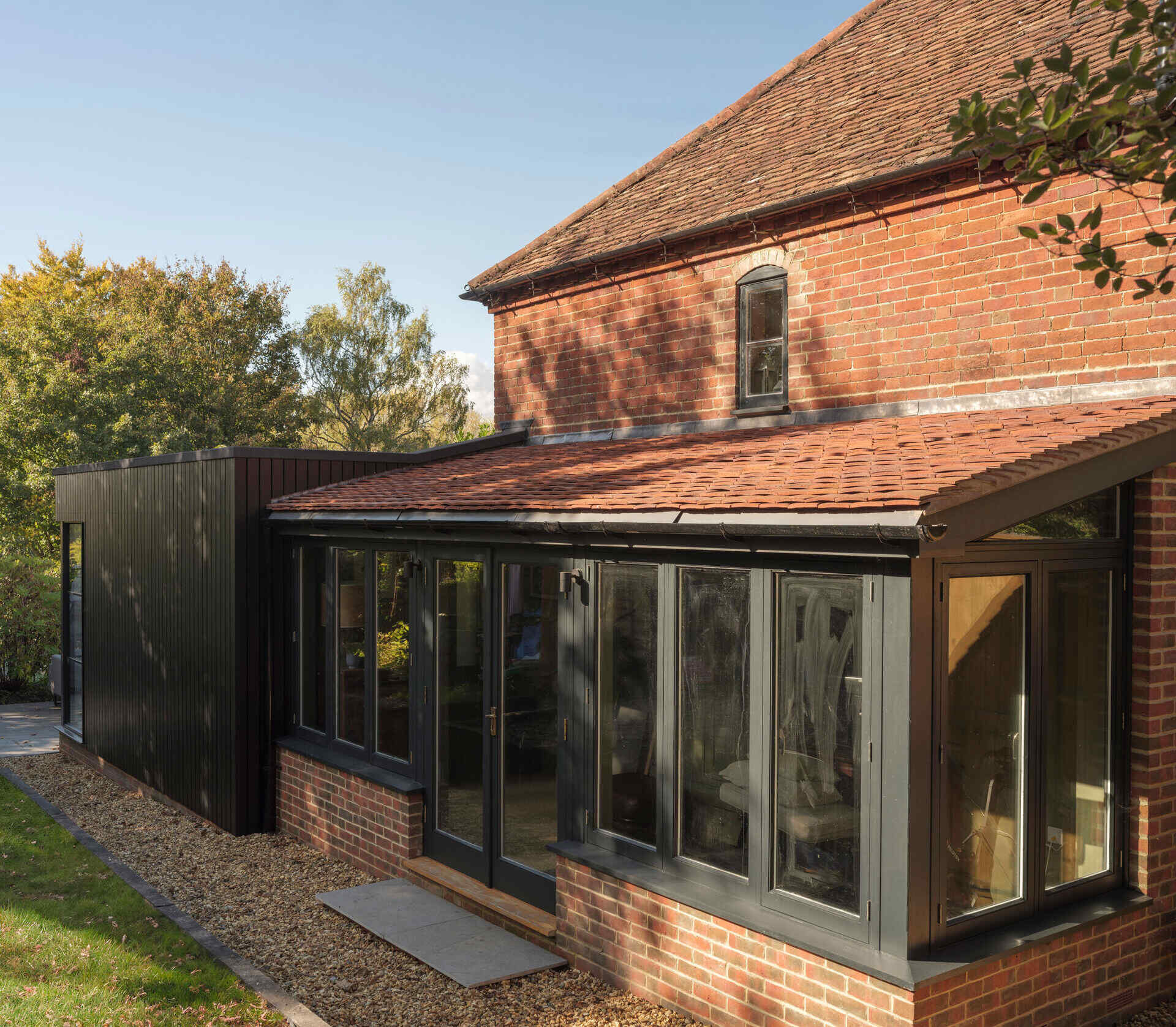 Traditional red brickwork, a pitched clay-tiled roof, and black-framed windows give this historic Hampshire cottage its character alongside a contemporary extension.