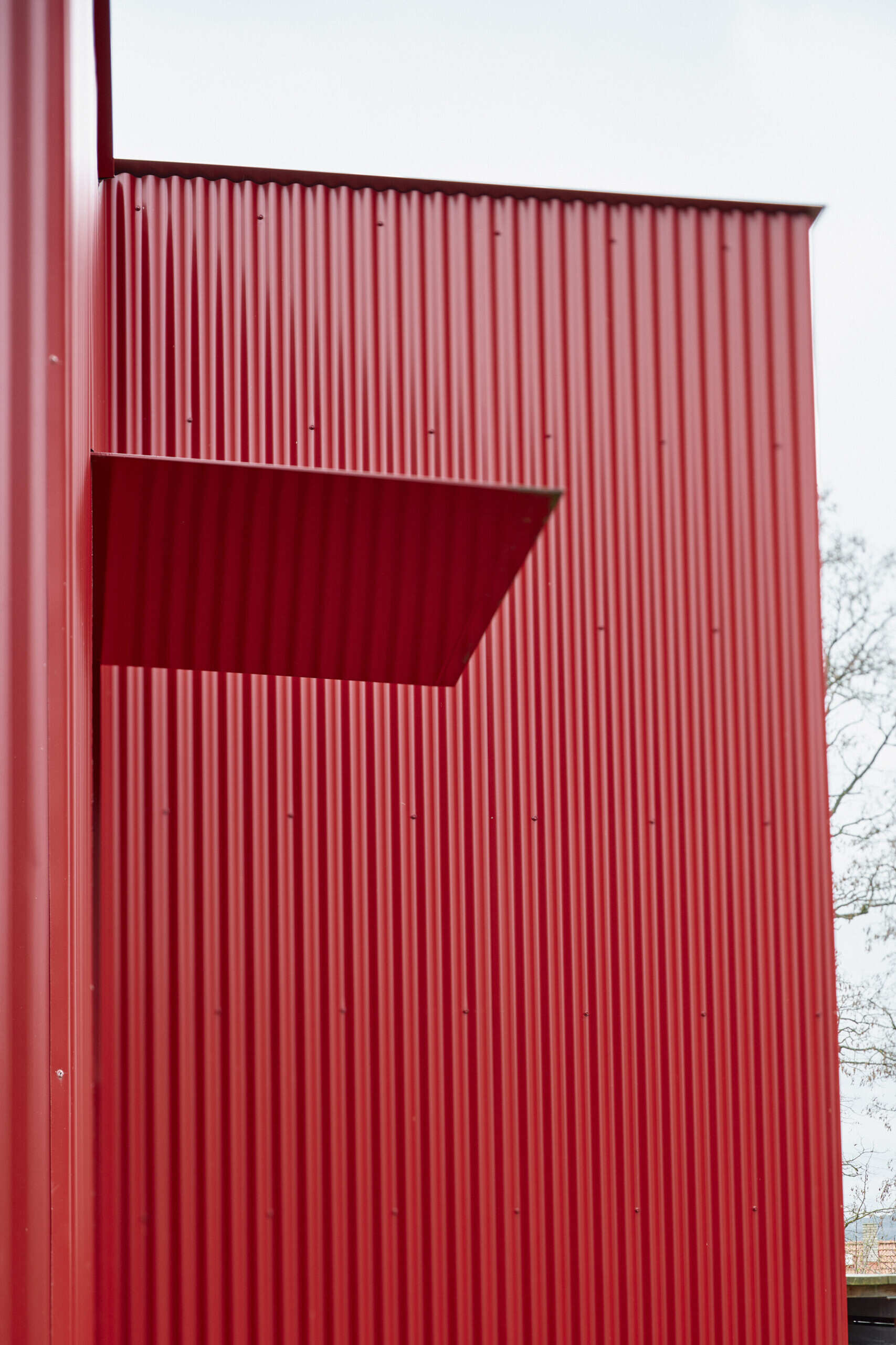 The relocated entrance to this home in Ne?ín, Czech Republic, is set into the new red corrugated metal extension by Facha architekti. Moving the doorway helped reorganise the interior while pine plywood brings warmth to the space inside.