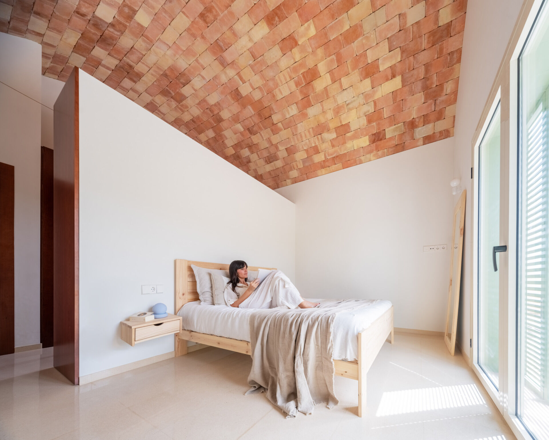 Explore the minimalist bedrooms at Casa Vereda in Spain, featuring curved brick ceilings, natural pine furniture, pale terrazzo floors, and Mediterranean shutters. Simple bedroom interiors with warm materials and contemporary Spanish design.