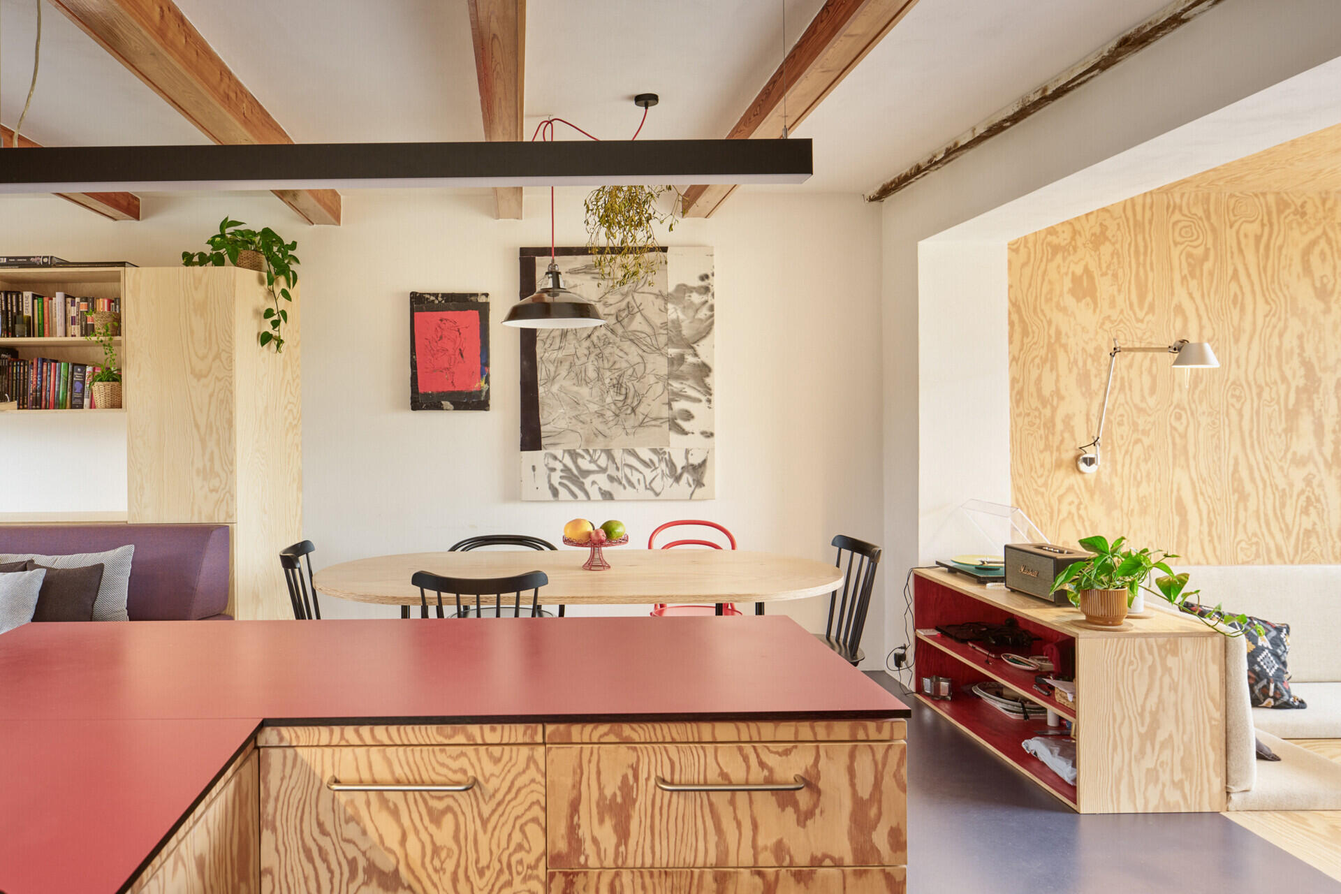 The redesigned kitchen and dining area in this Ne?ín home by Facha architekti combines custom pine plywood cabinetry, natural linoleum flooring and a rotating wood-burning stove within the reworked ground floor.