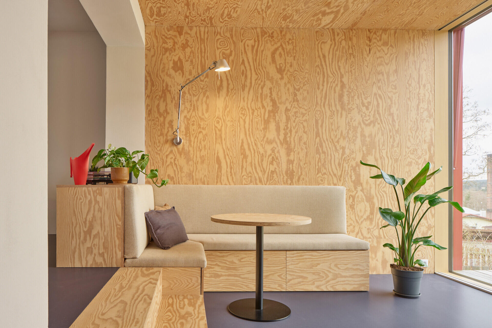 The living room in this Ne?ín home by Facha architekti uses pine plywood, built-in seating and integrated storage to make a compact new addition feel warm, practical and spacious.