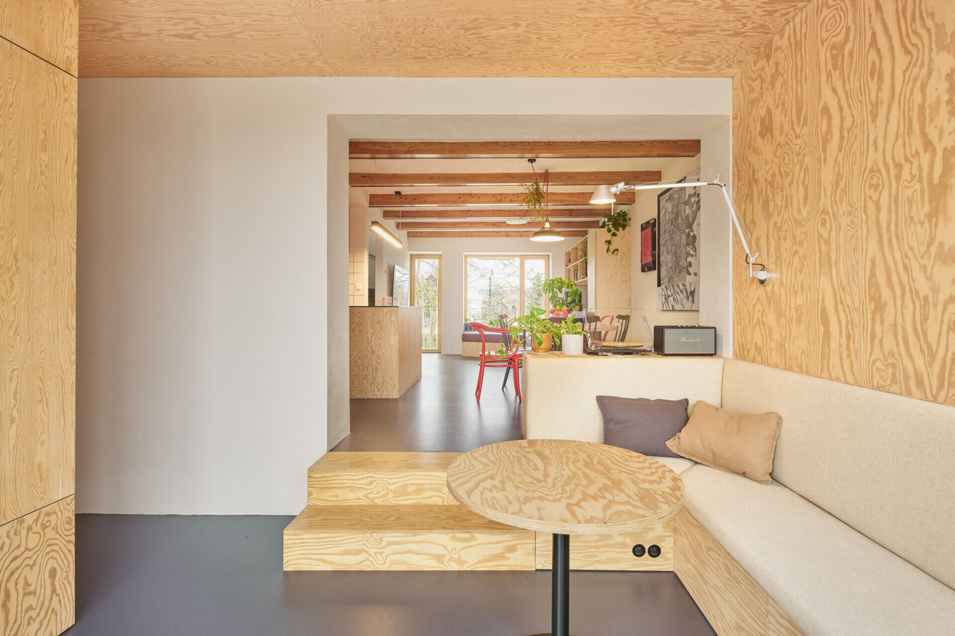 The living room in this Ne?ín home by Facha architekti uses pine plywood, built-in seating and integrated storage to make a compact new addition feel warm, practical and spacious.