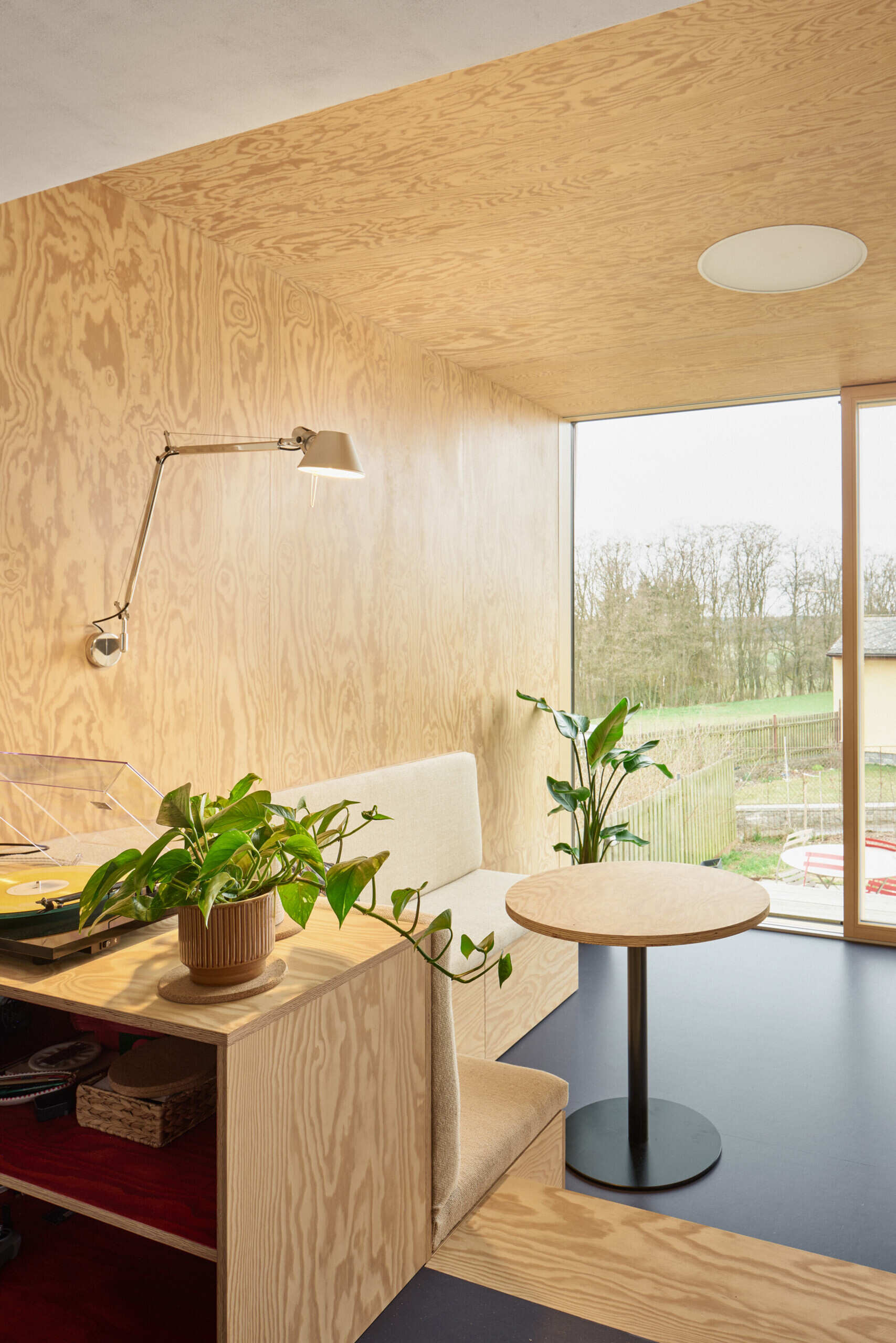 The living room in this Ne?ín home by Facha architekti uses pine plywood, built-in seating and integrated storage to make a compact new addition feel warm, practical and spacious.