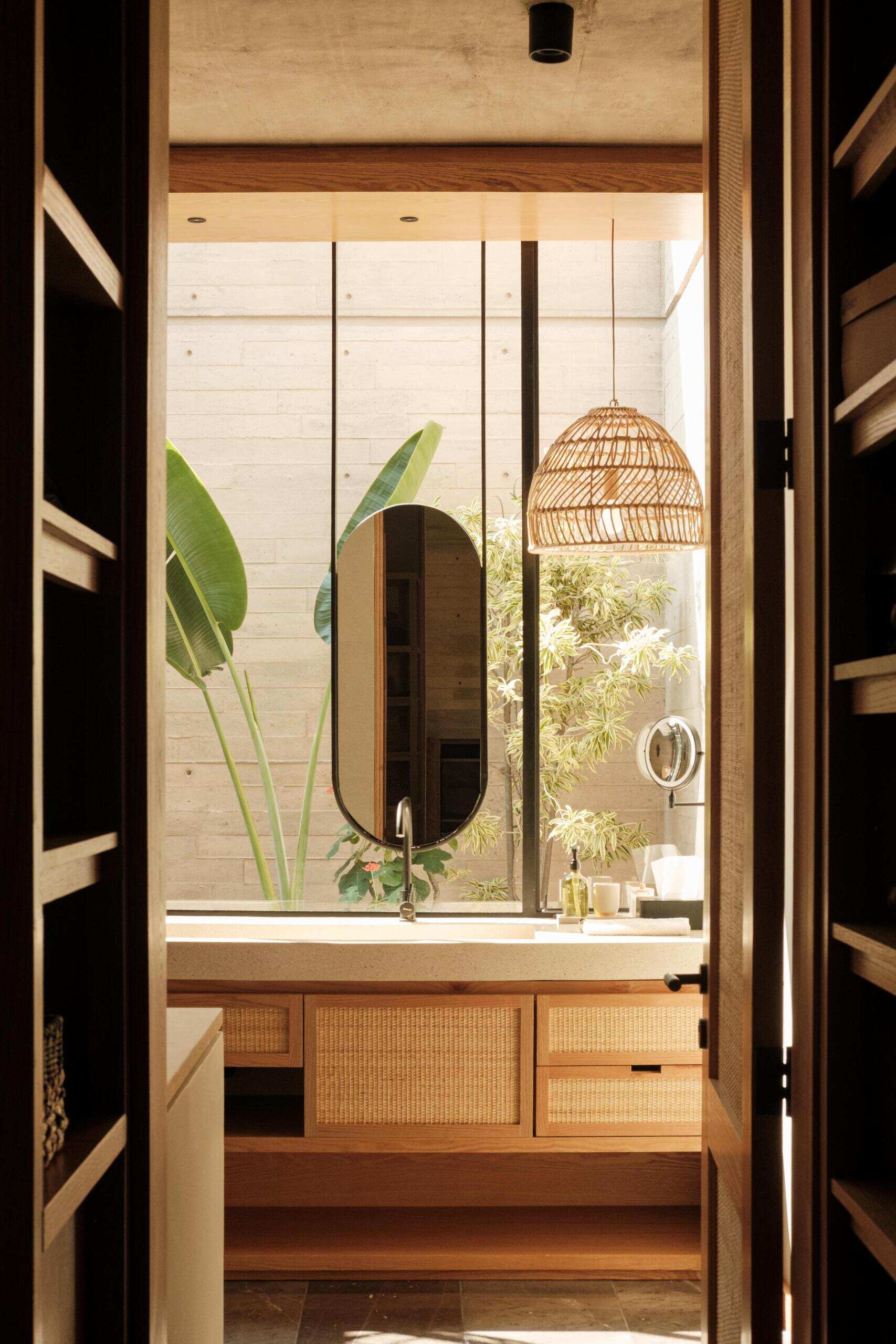 Explore a modern primary bedroom suite featuring a private sitting area, built-in bookshelves, woven sliding doors, a bedroom with geometric breeze-block screens, and a bathroom overlooking a planted courtyard.