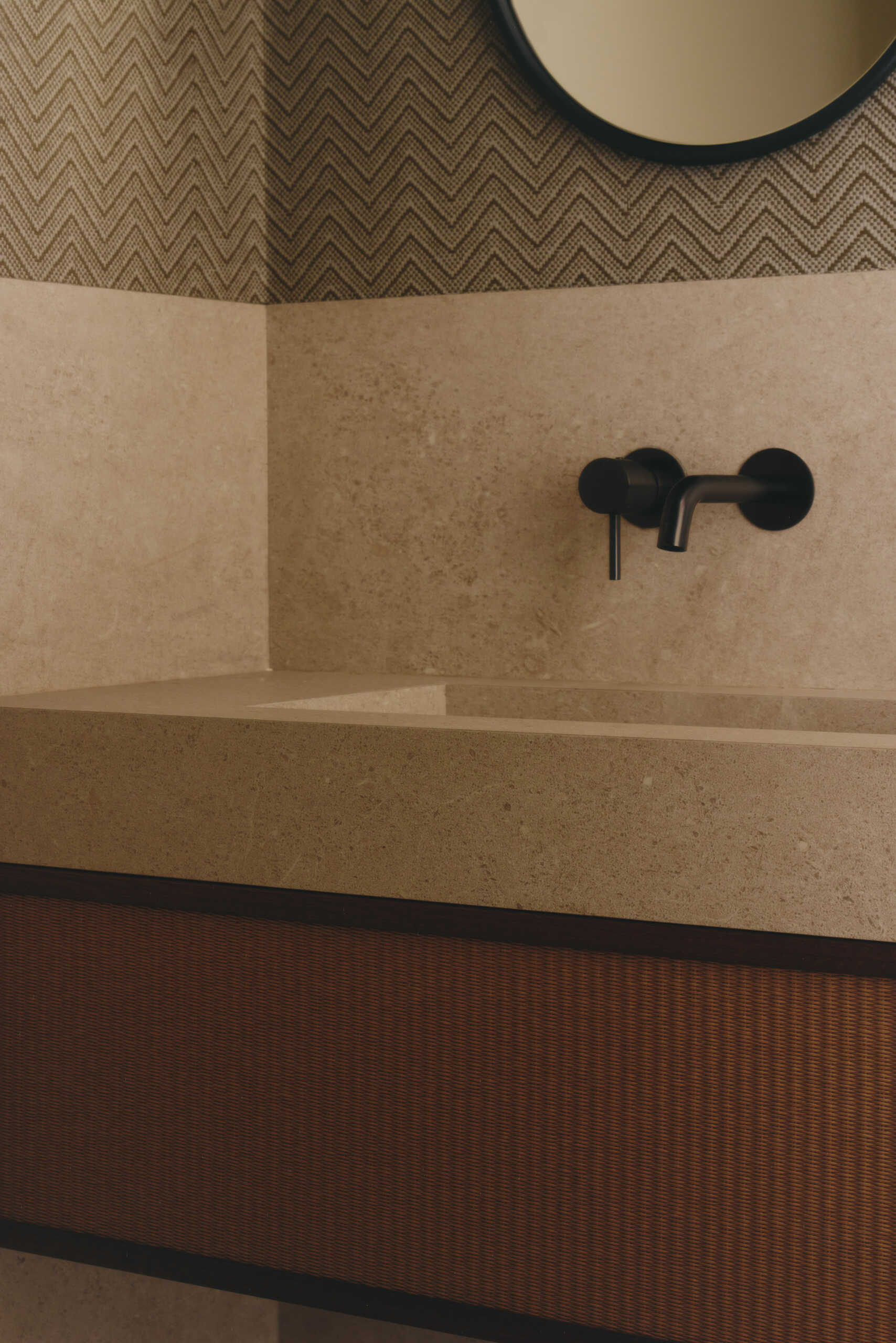 Discover minimalist modern bathrooms with pale stone-look vanities, integrated sinks, oval mirrors, matte black faucets, natural woven cabinetry, and large windows overlooking greenery.