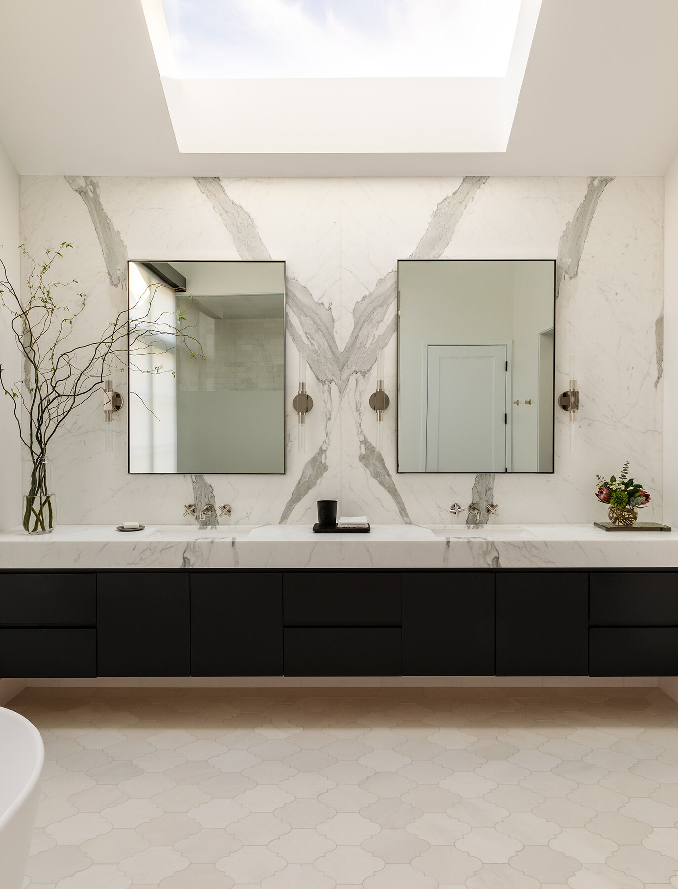 Explore the Atherton Residence bathroom by Paulina Carcach Studio, featuring a freestanding tub, walk-in shower, skylight, grey-veined marble walls and a long matte black double vanity.