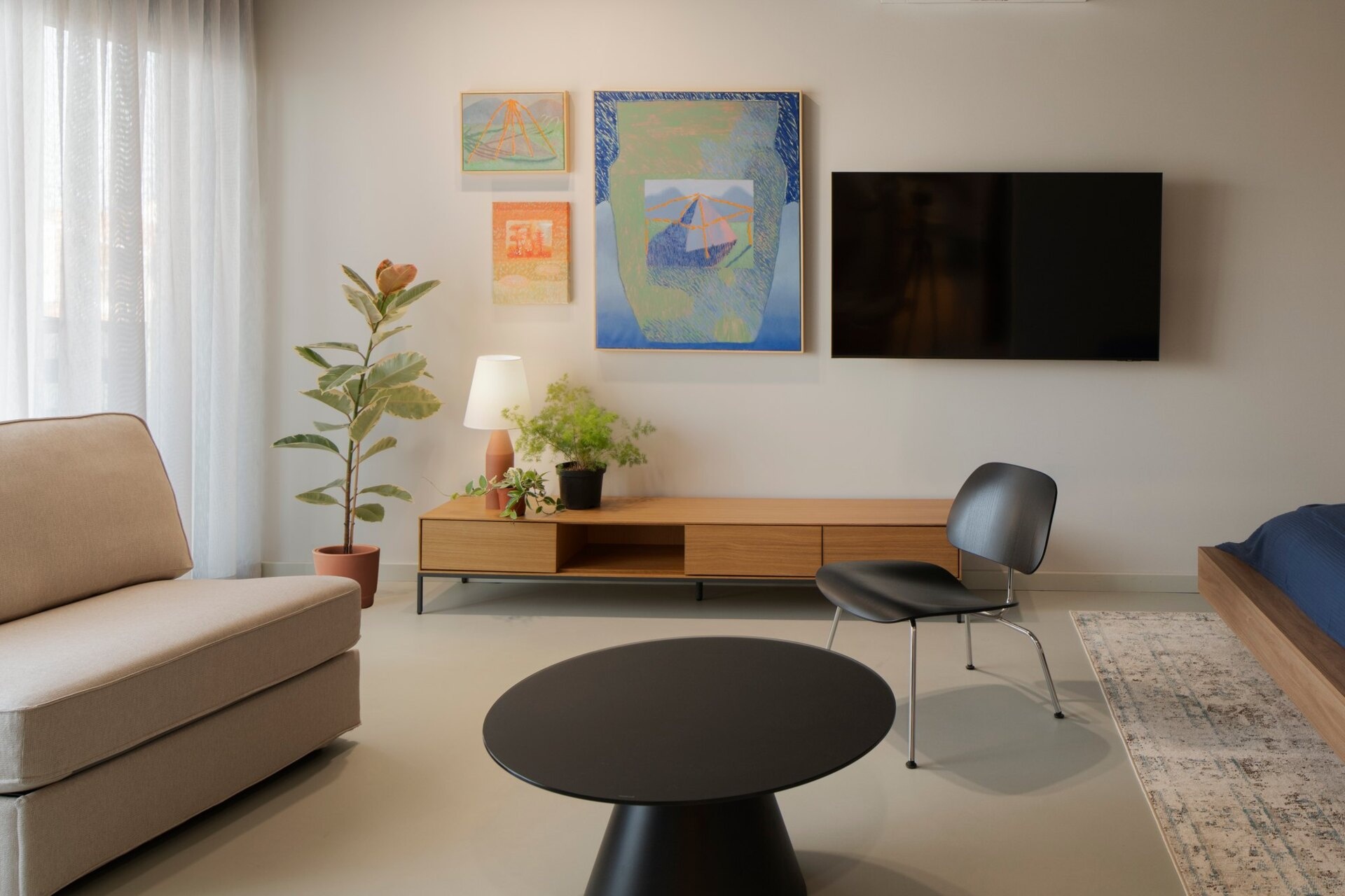 Discover a guest bedroom at Arc House, with a modern timber bed, black lounge chair, low wooden storage cabinet, colourful gallery wall and contemporary bedroom furniture in a Croatian villa.