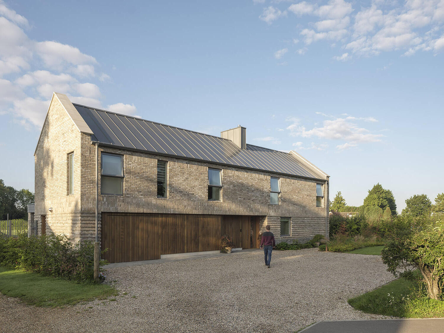 A contemporary home in Suffolk by House Form takes inspiration from traditional English longhouse architecture, combining a pitched roof, pale brick exterior, and modern design.