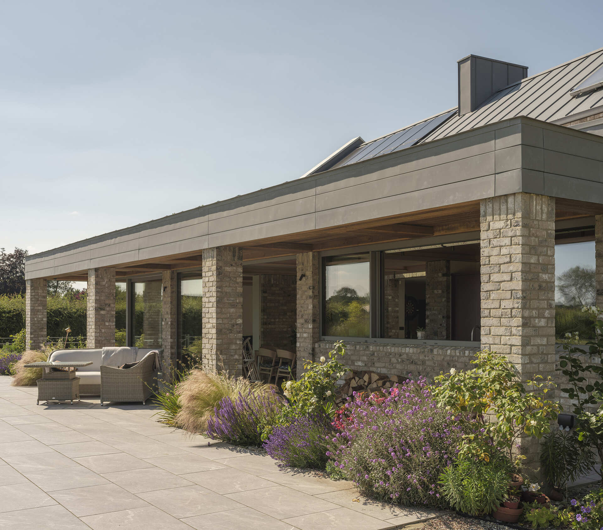 This energy-efficient home features smaller north-facing windows and a glass-filled garden pavilion, using orientation and solar shading to improve comfort.