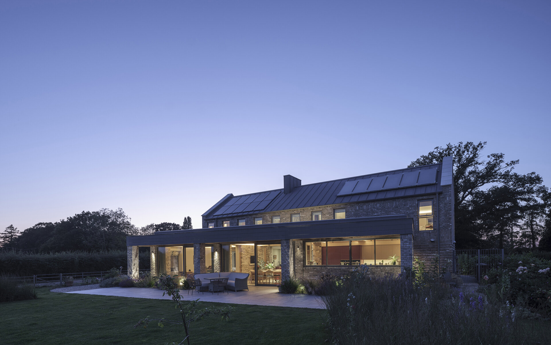 This energy-efficient home features smaller north-facing windows and a glass-filled garden pavilion, using orientation and solar shading to improve comfort.